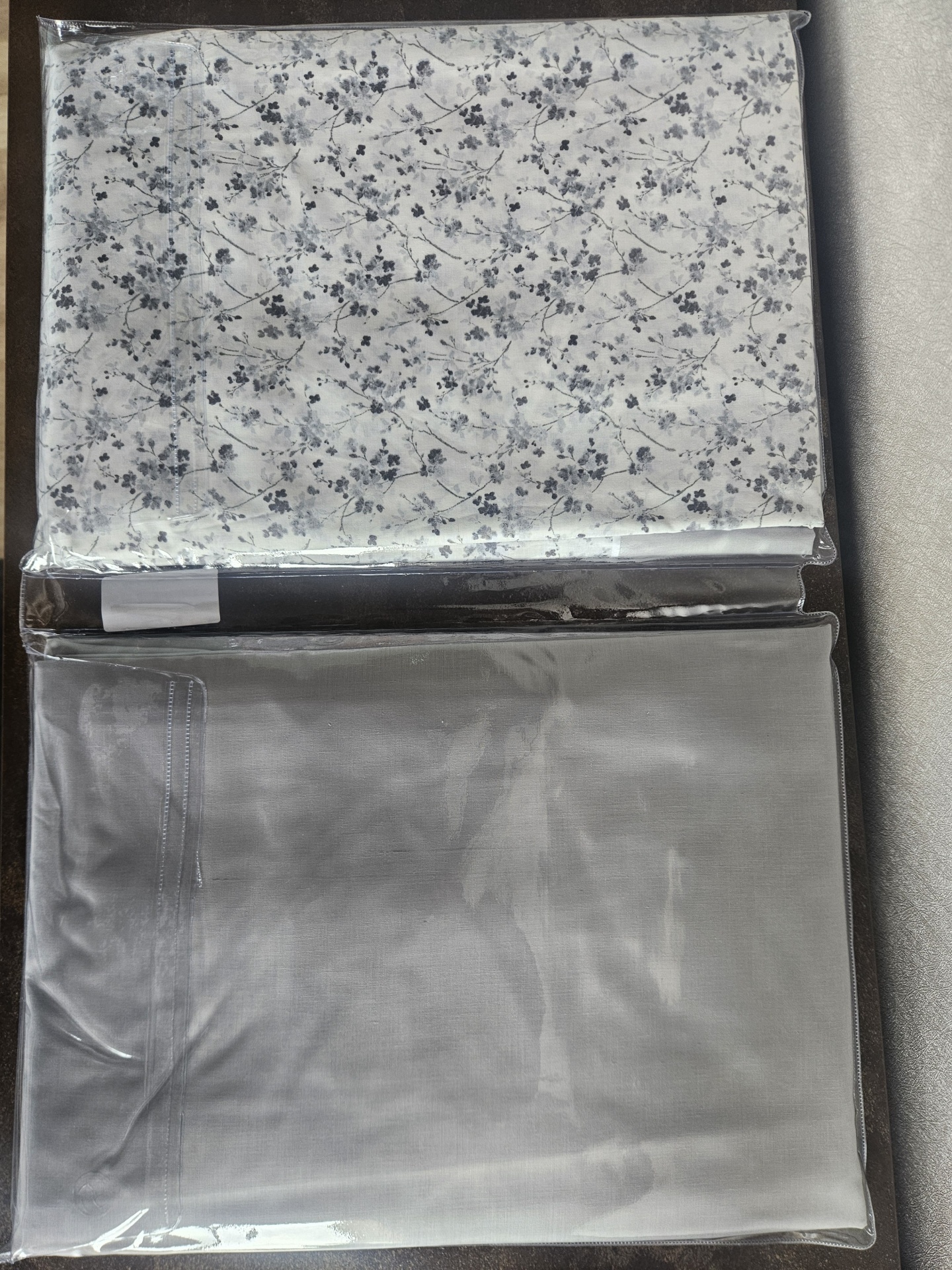 Conjunto de têxteis para cama embalados em plástico transparente com padrão floral e cor cinza sólido