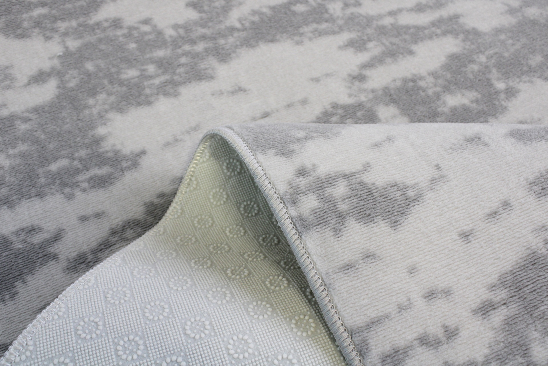 Tapete cinzento com padrão abstrato e verso antiderrapante branco