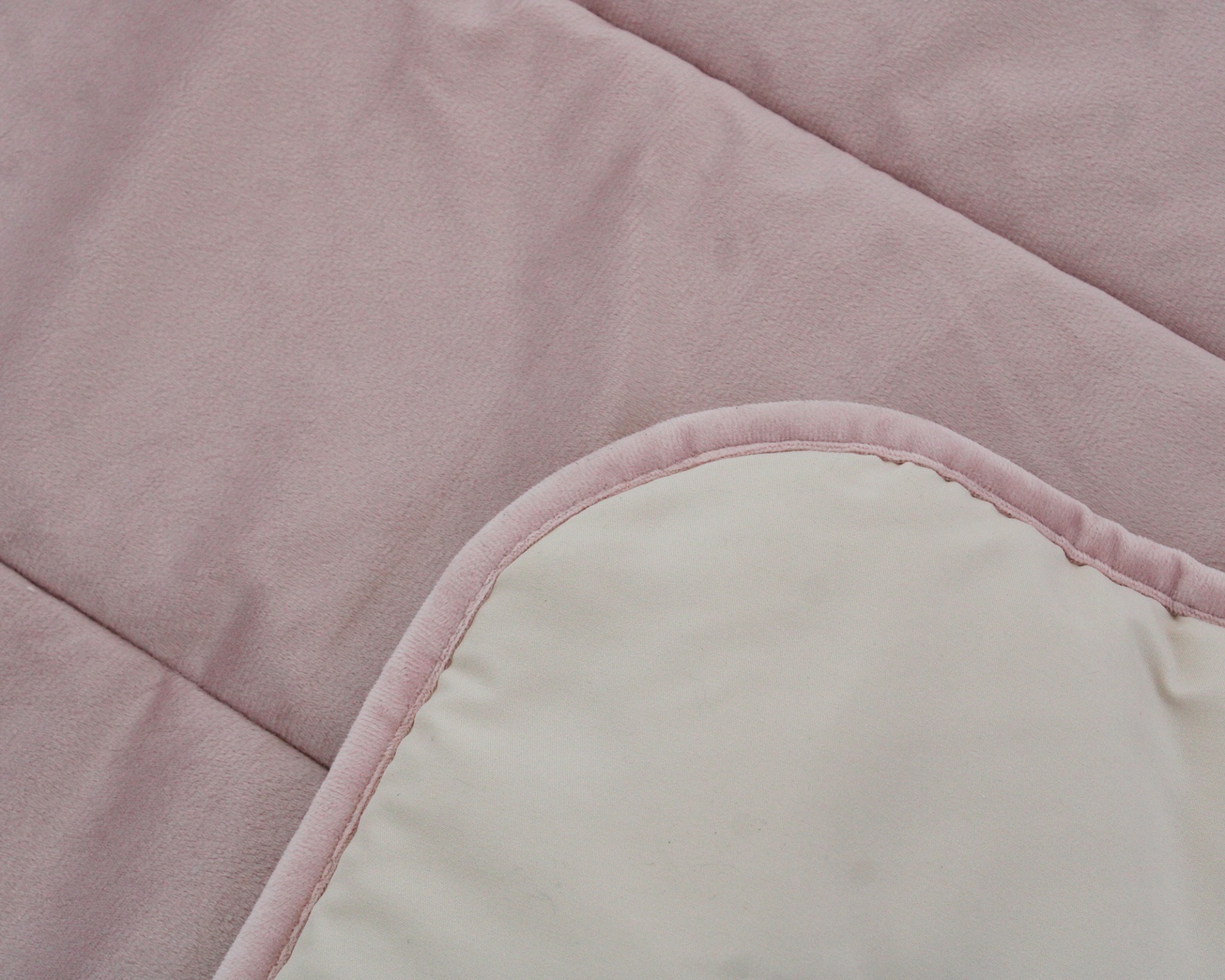 Cobertor ou manta em tecido rosa pastel com parte reversível branca.