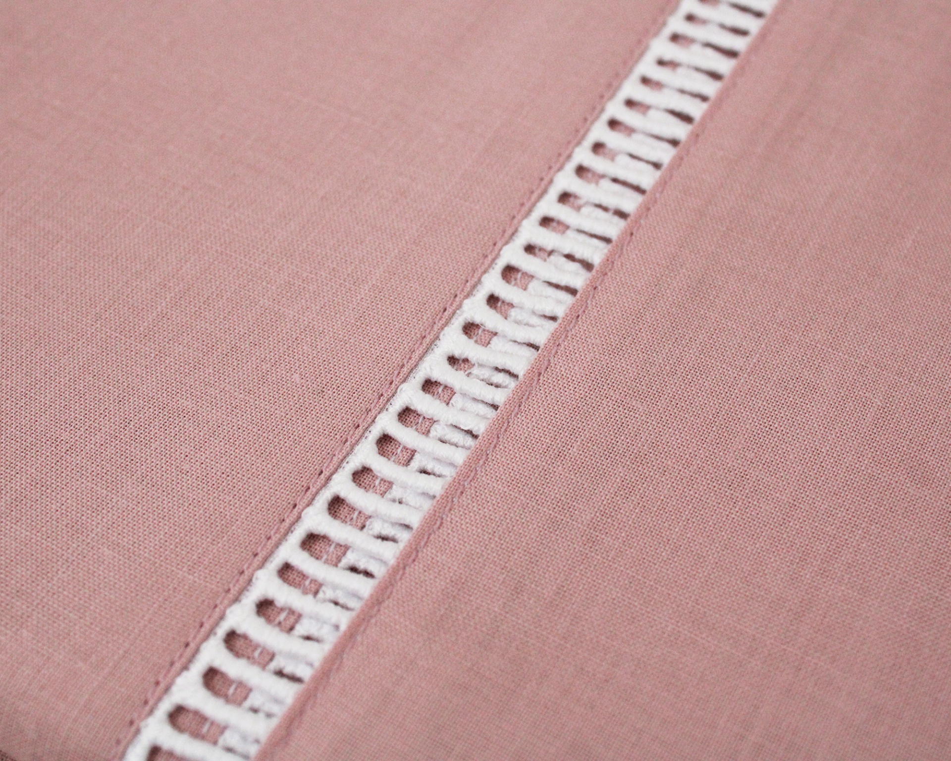 Tecido rosa com faixa decorativa branca com padrão de buracos