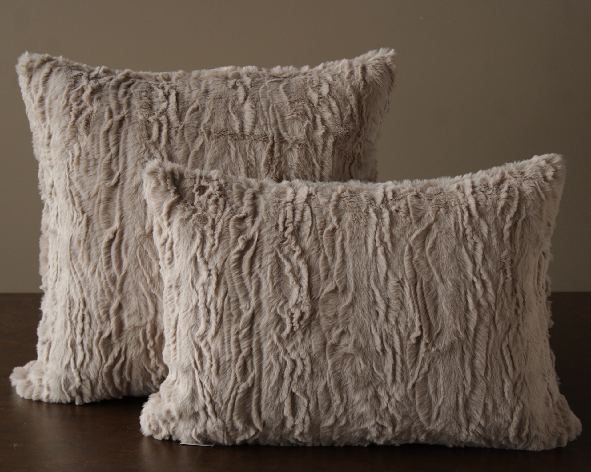 Duas almofadas decorativas de pelúcia bege claro com textura felpuda.