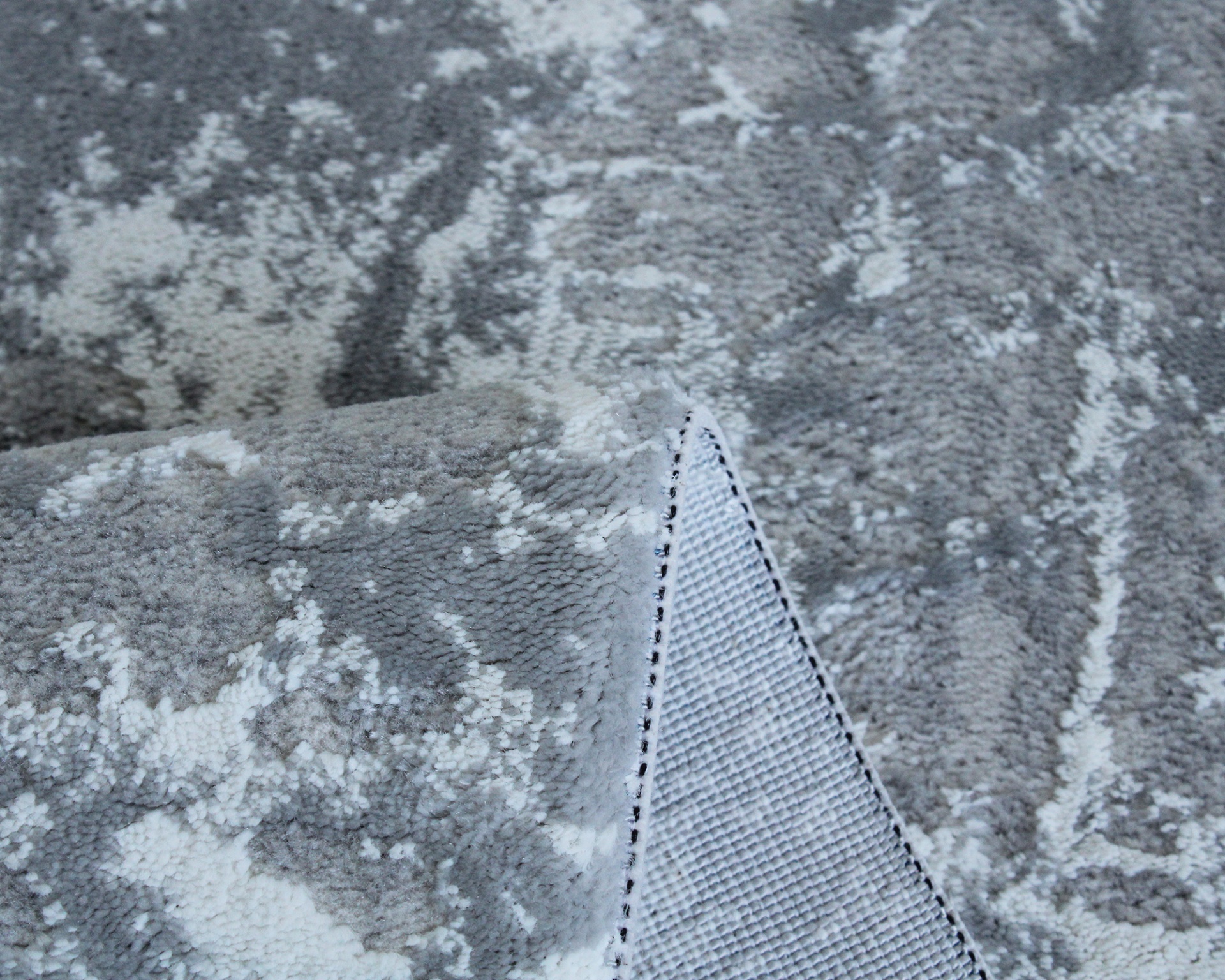 tapete cinza com padrão abstrato e dobra mostrando o verso