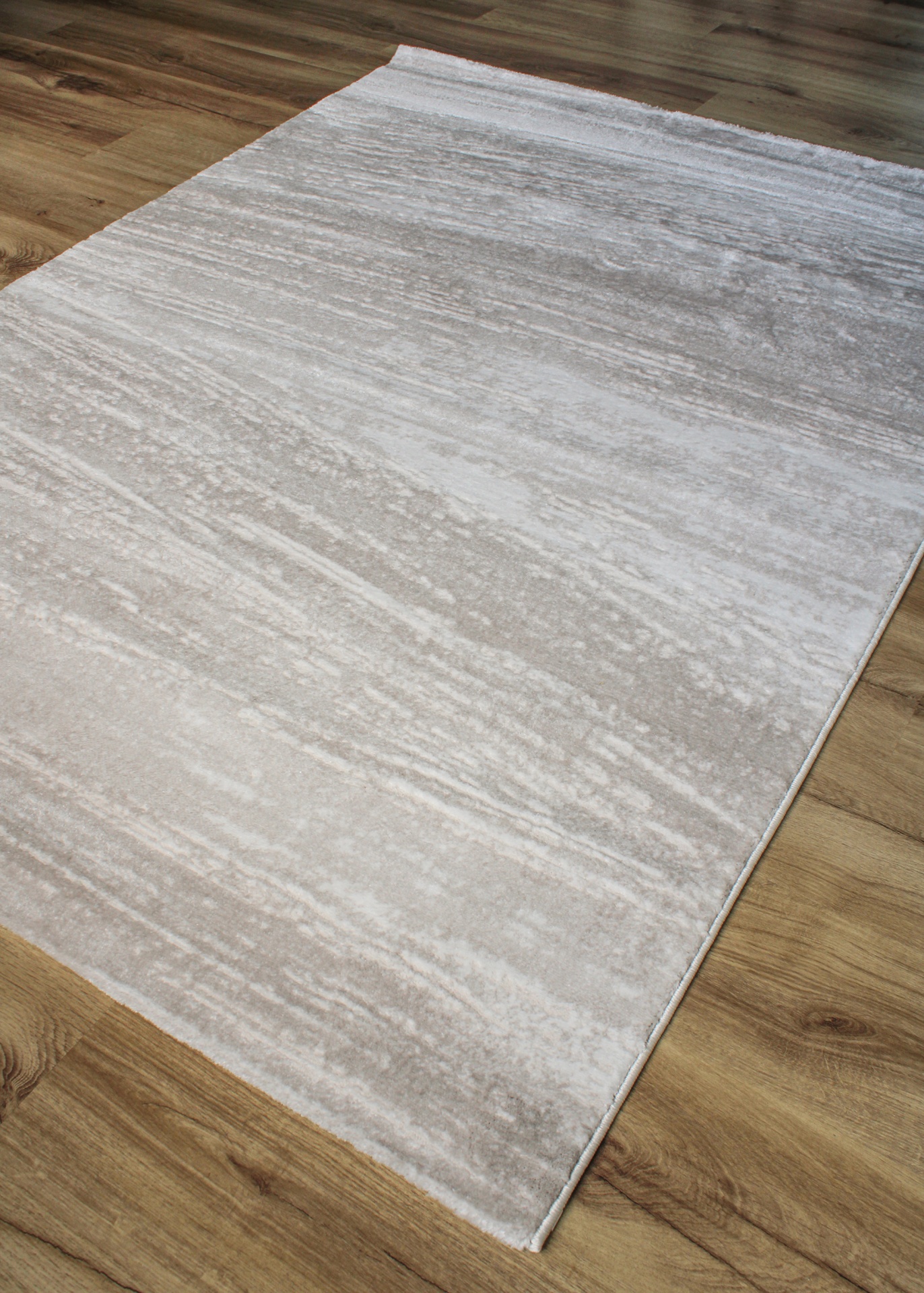 Tapete bege e cinza claro com padrão abstrato sobre chão de madeira