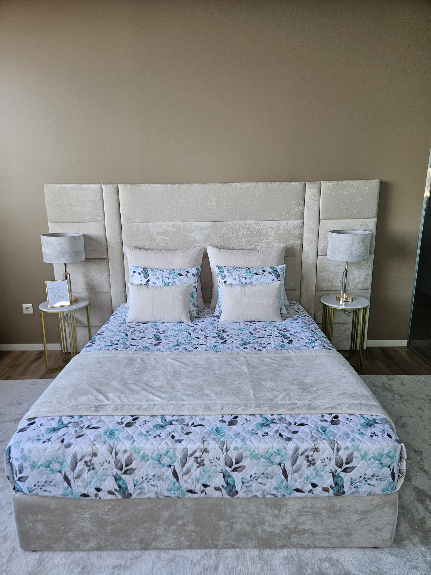 Cama estofada com cabeceira alta cinza claro e roupa de cama floral