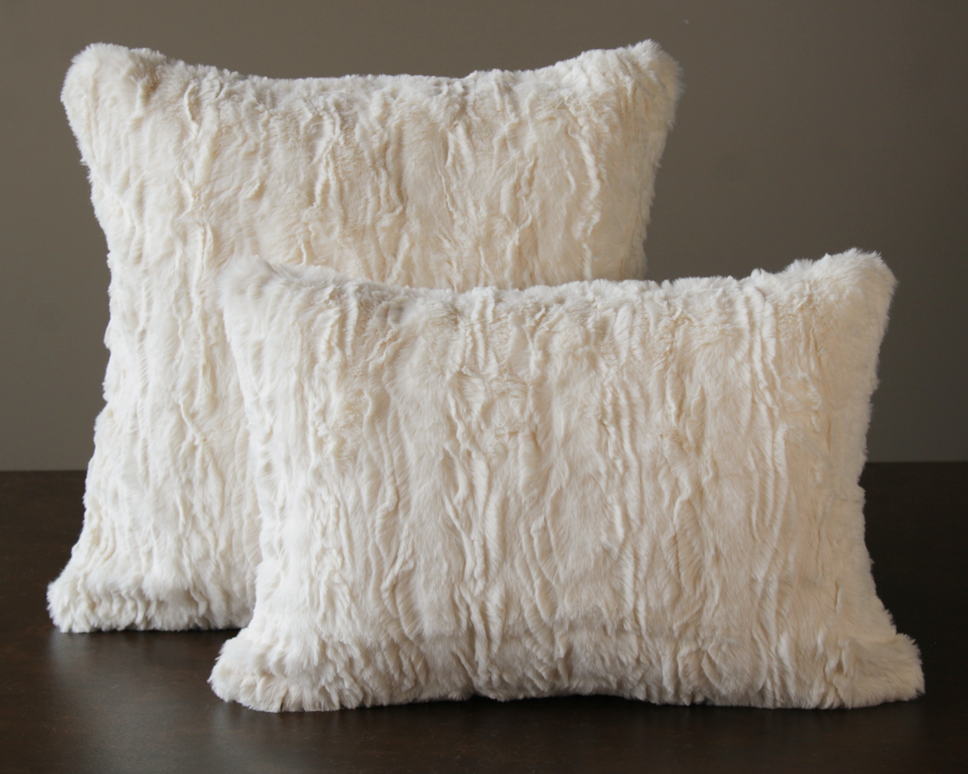 Duas almofadas felpudas brancas em fundo neutro