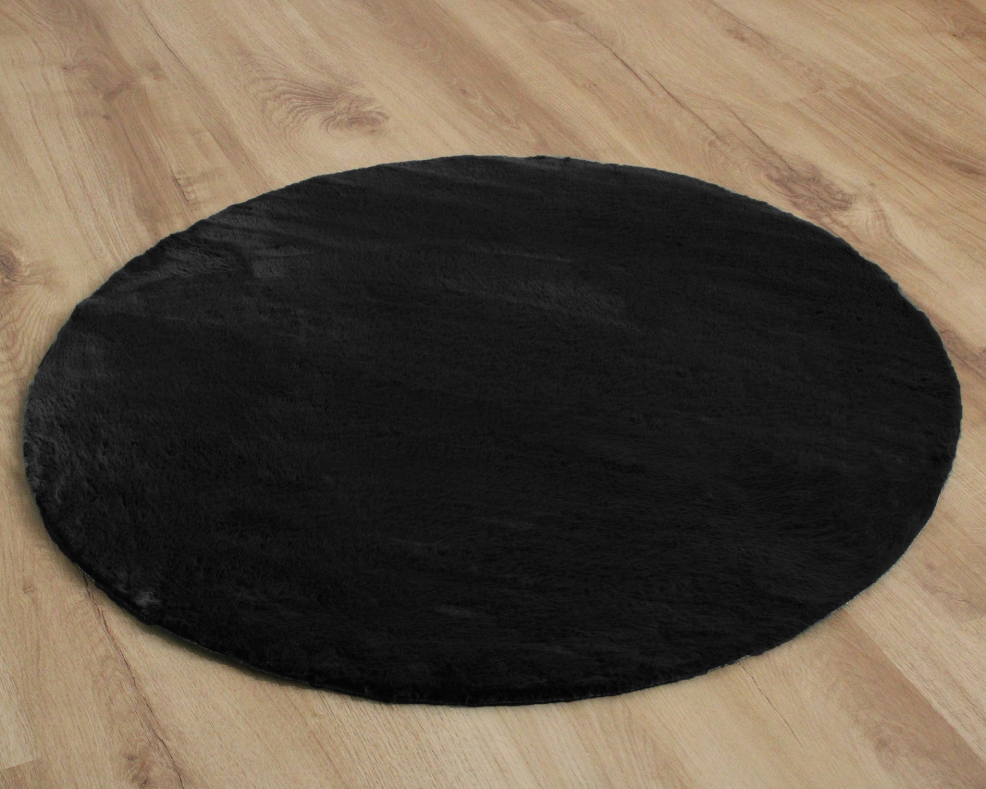 Tapete redondo preto sobre chão de madeira