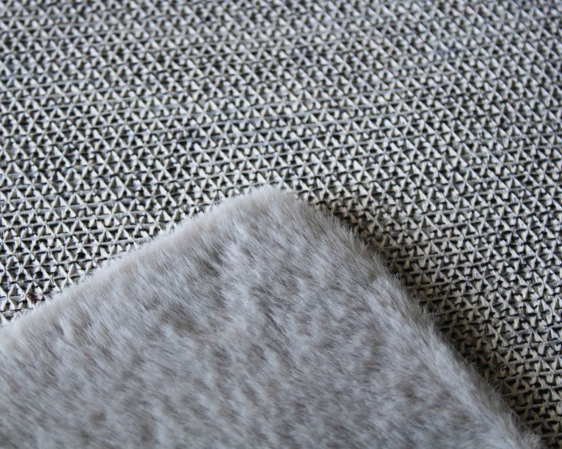 Tapete cinzento felpudo sobre piso com padrão geométrico cinza