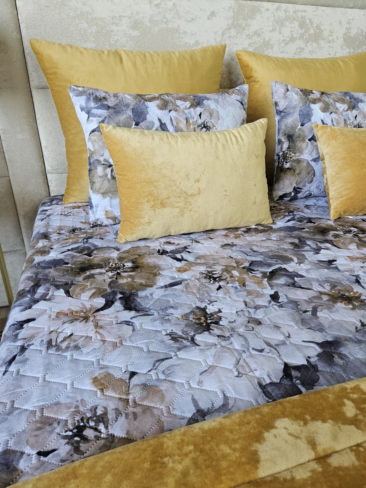 Cama com almofadas estampadas florais e almofadas amarelas aveludadas