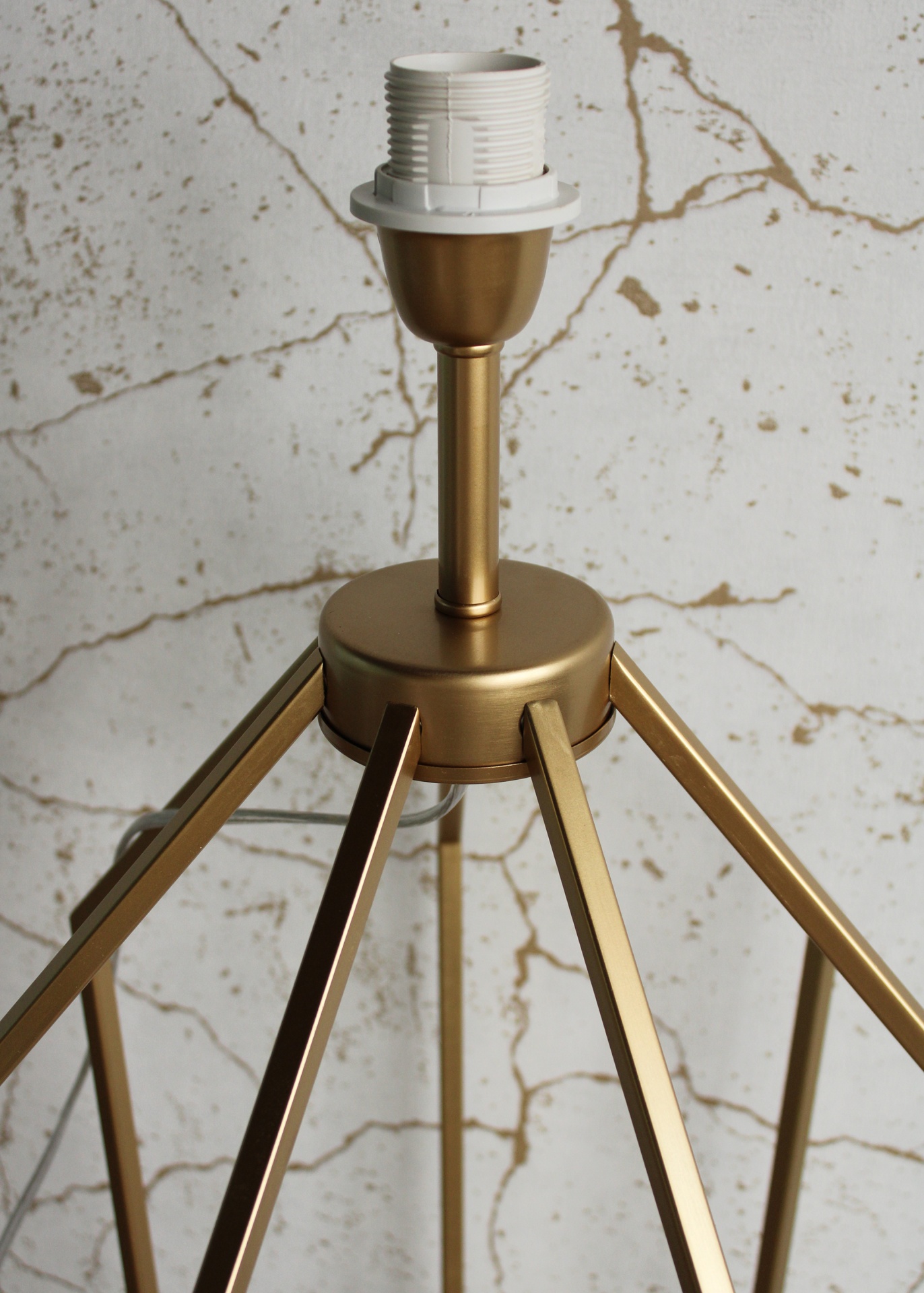 Candeeiro de teto dourado com suporte branco sobre fundo marmoreado