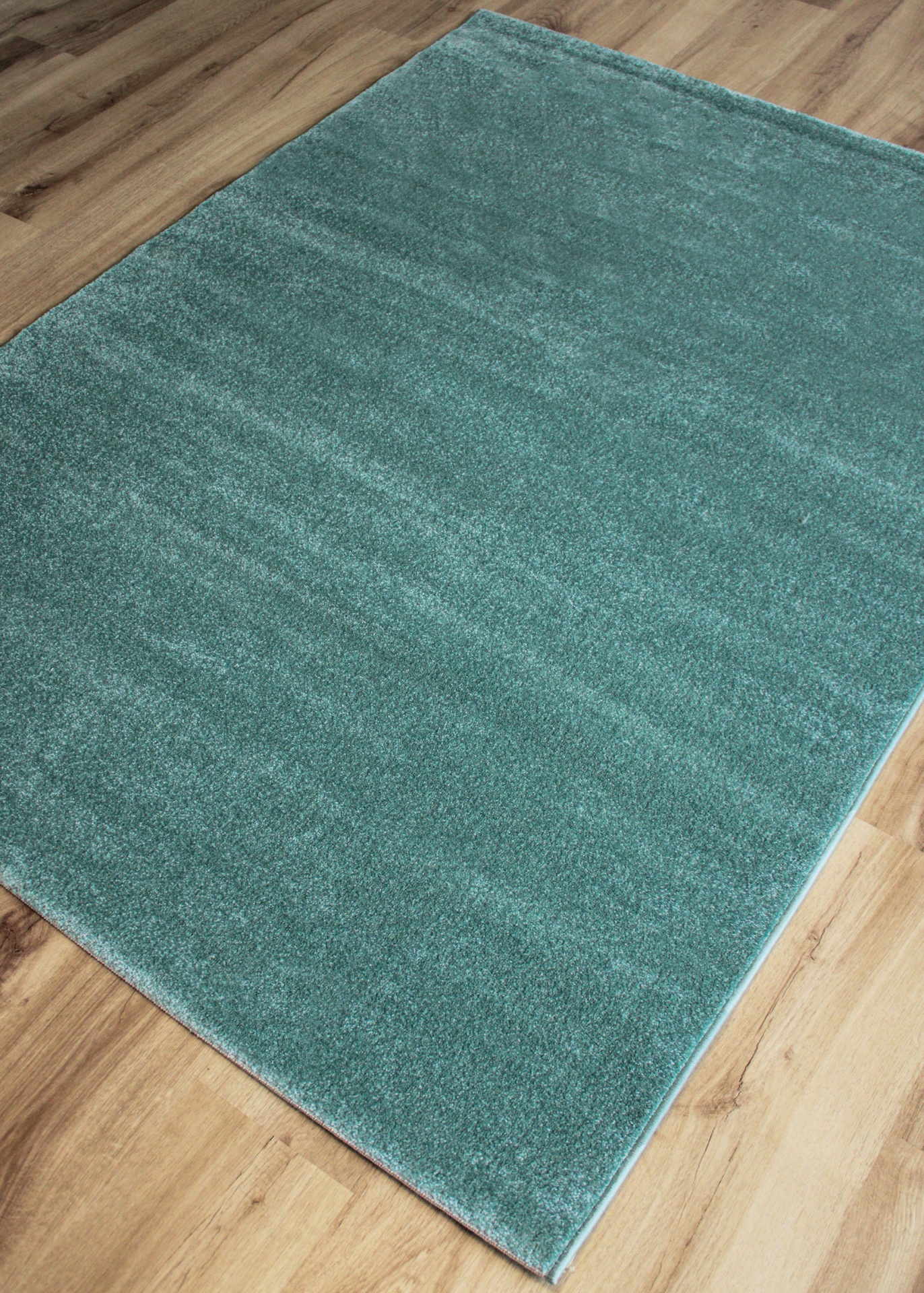 Tapete felpudo verde sobre piso de madeira clara