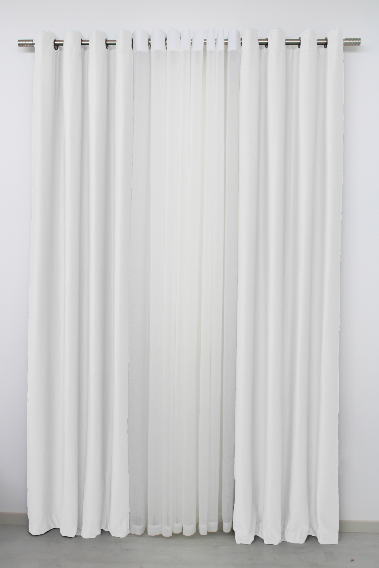 Cortinas brancas duplas, tecido opaco e tule, com ilhós prateados numa varão metálico