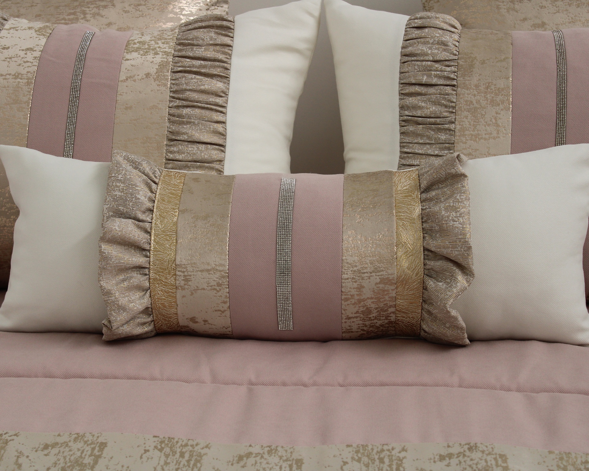 Conjunto de almofadas decorativas rosa, dourado e branco sobre cama