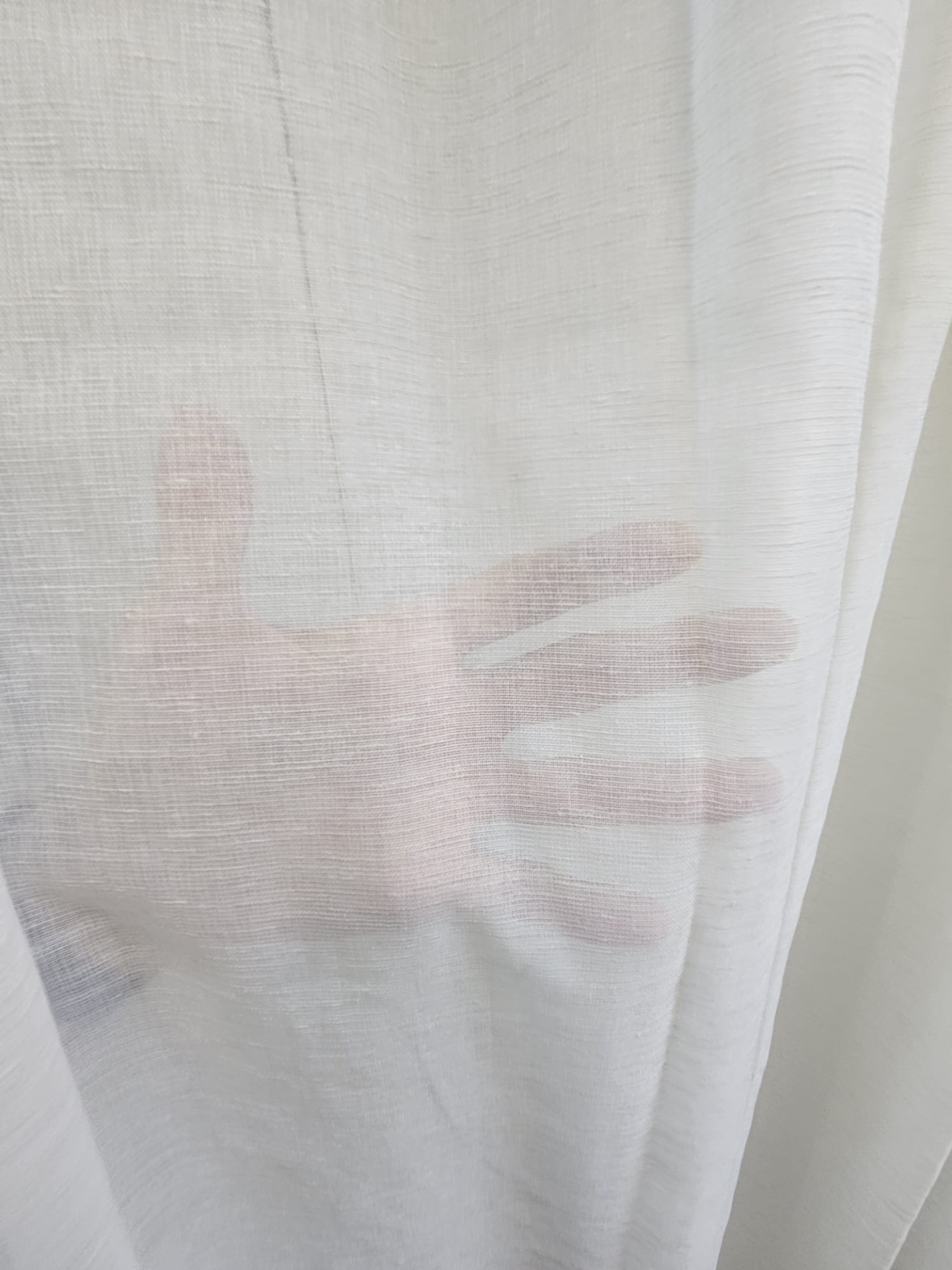 Cortina branca transparente com mão visível por trás