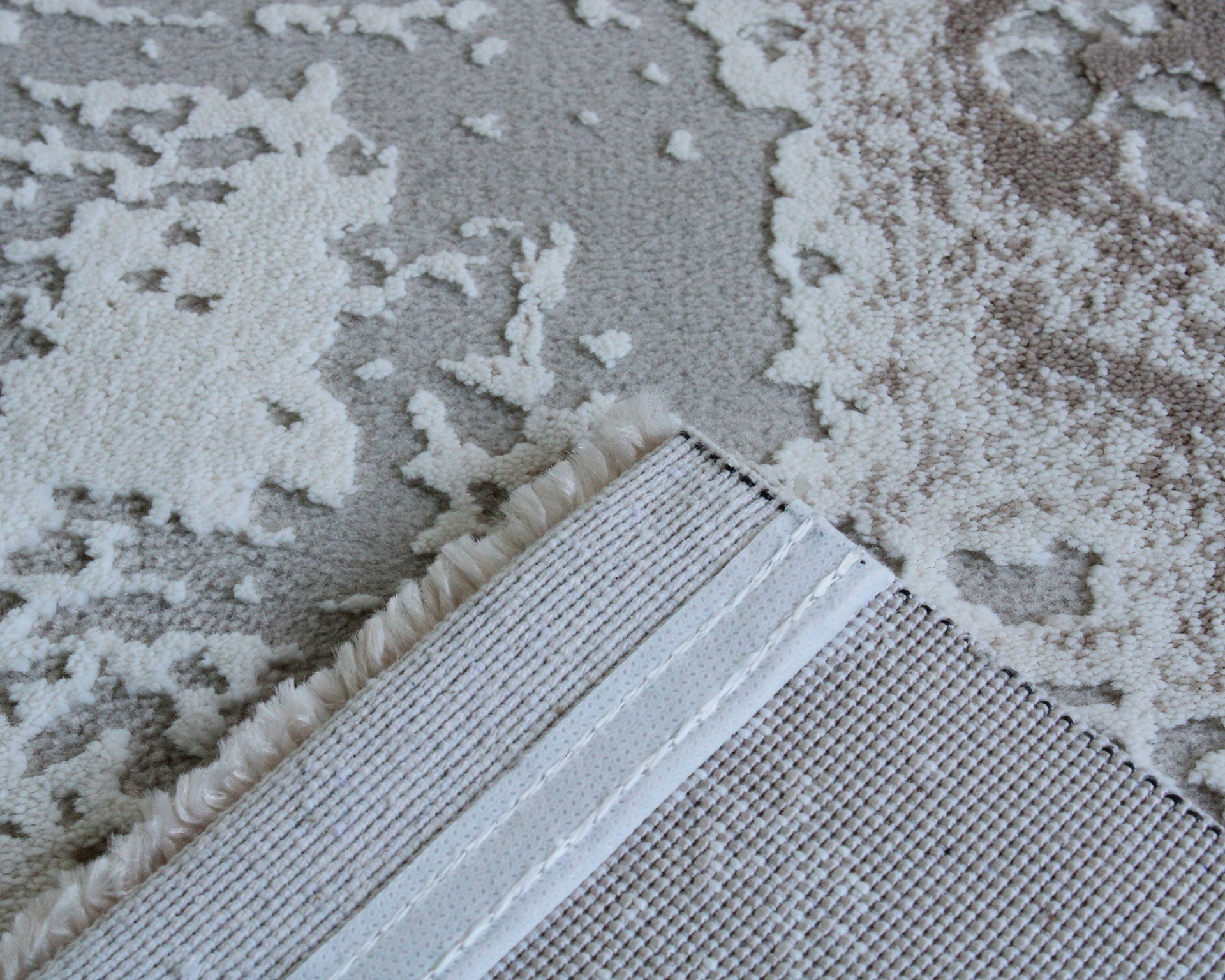 Tapete cinza e bege com padrão abstrato e franjas na borda