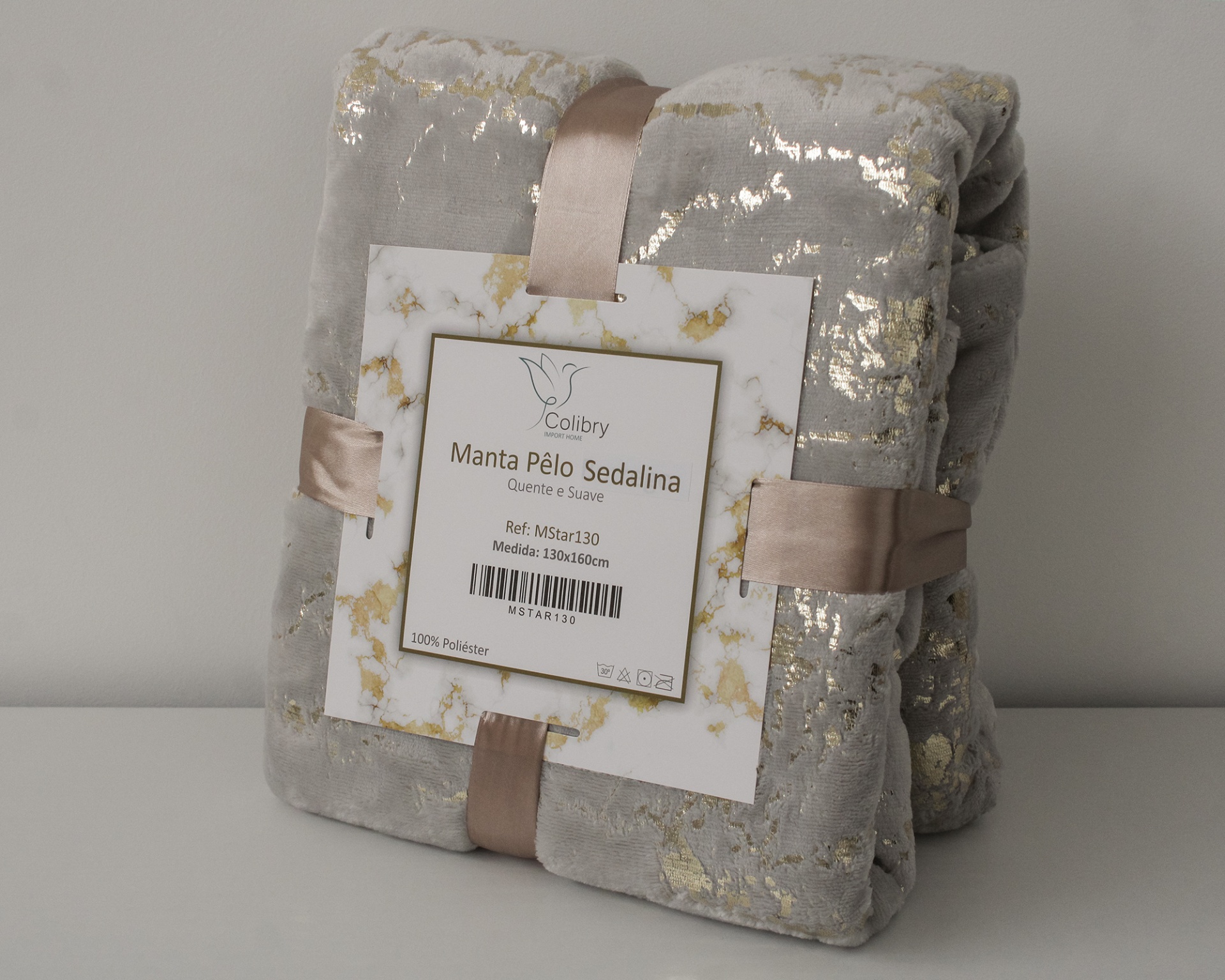 Manta cinzenta com padrão dourado, embalada com fita e etiqueta branca