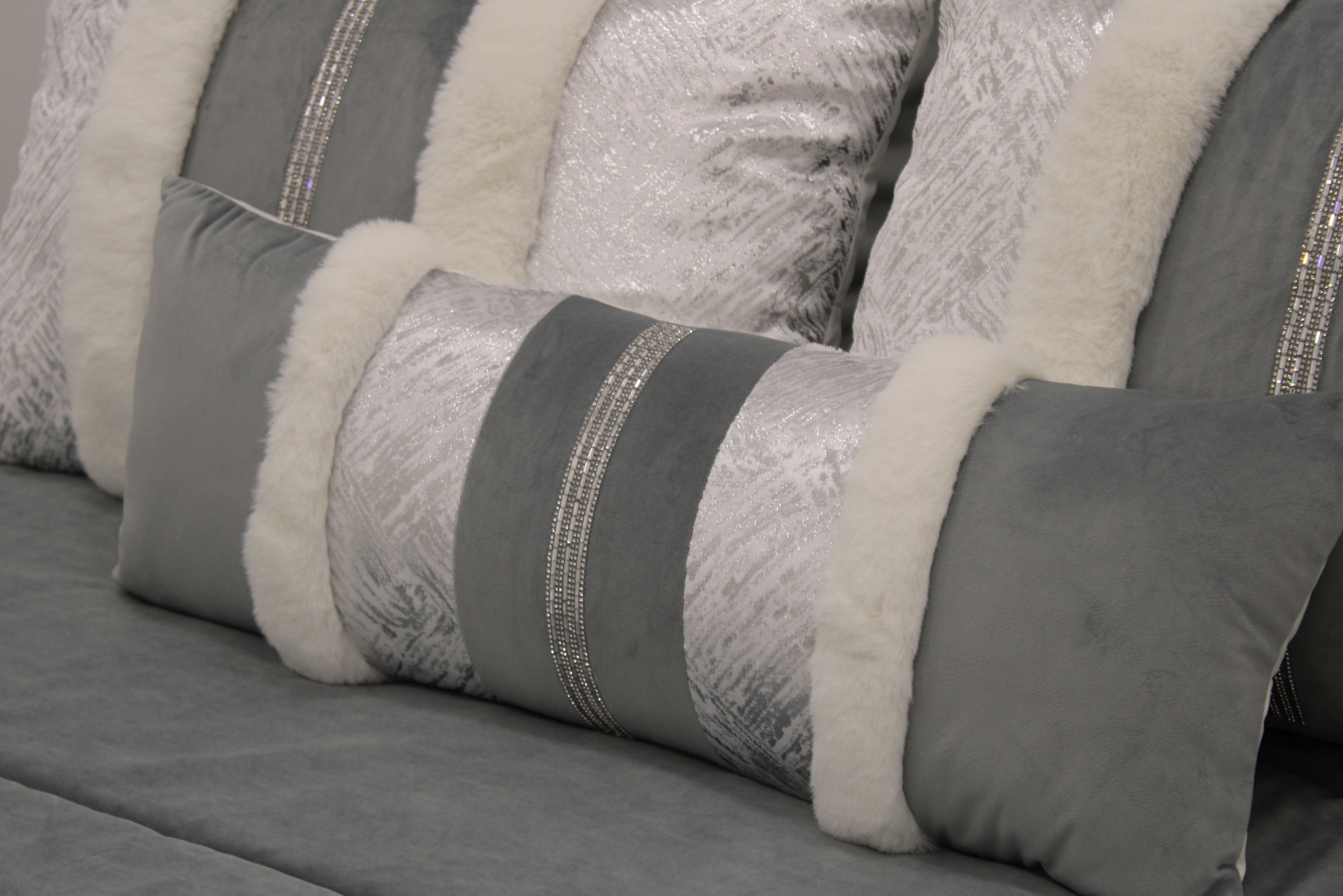 Almofadas decorativas cinza com faixas prateadas e bordas felpudas brancas