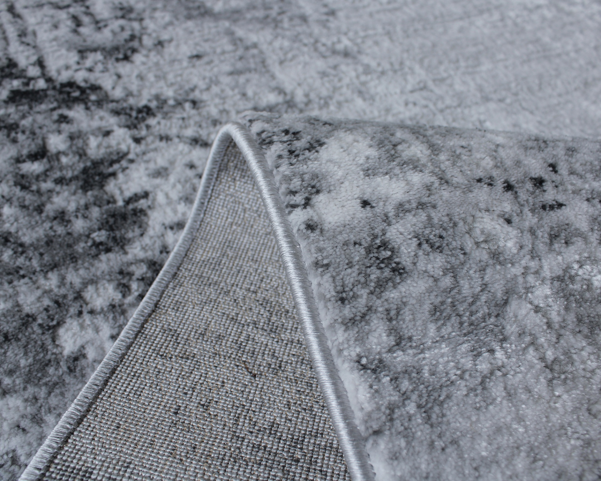 Tapete cinza com padrão abstrato e borda costurada