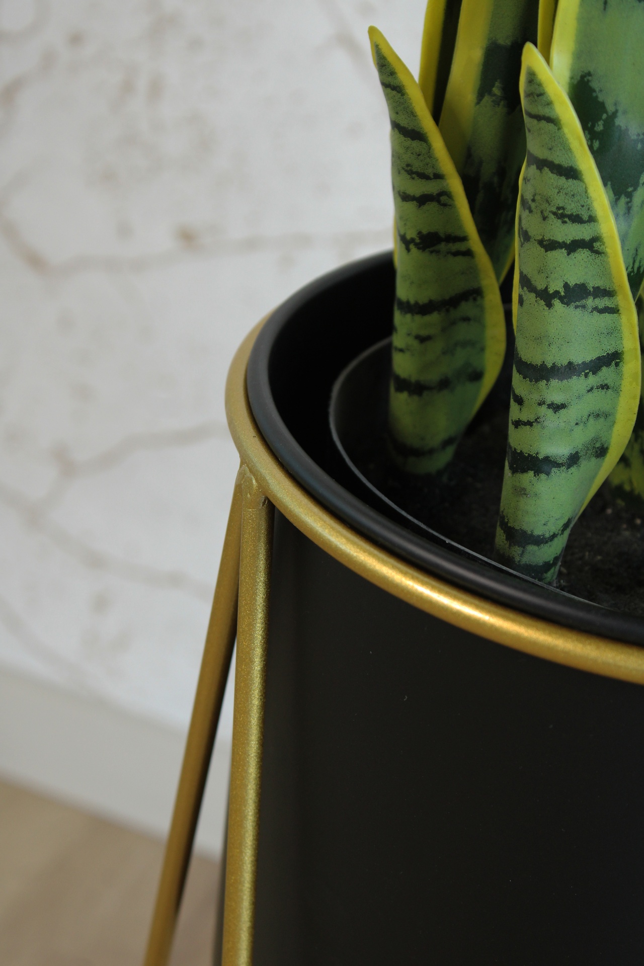 Vaso preto e dourado com planta de folhas verdes e amarelas