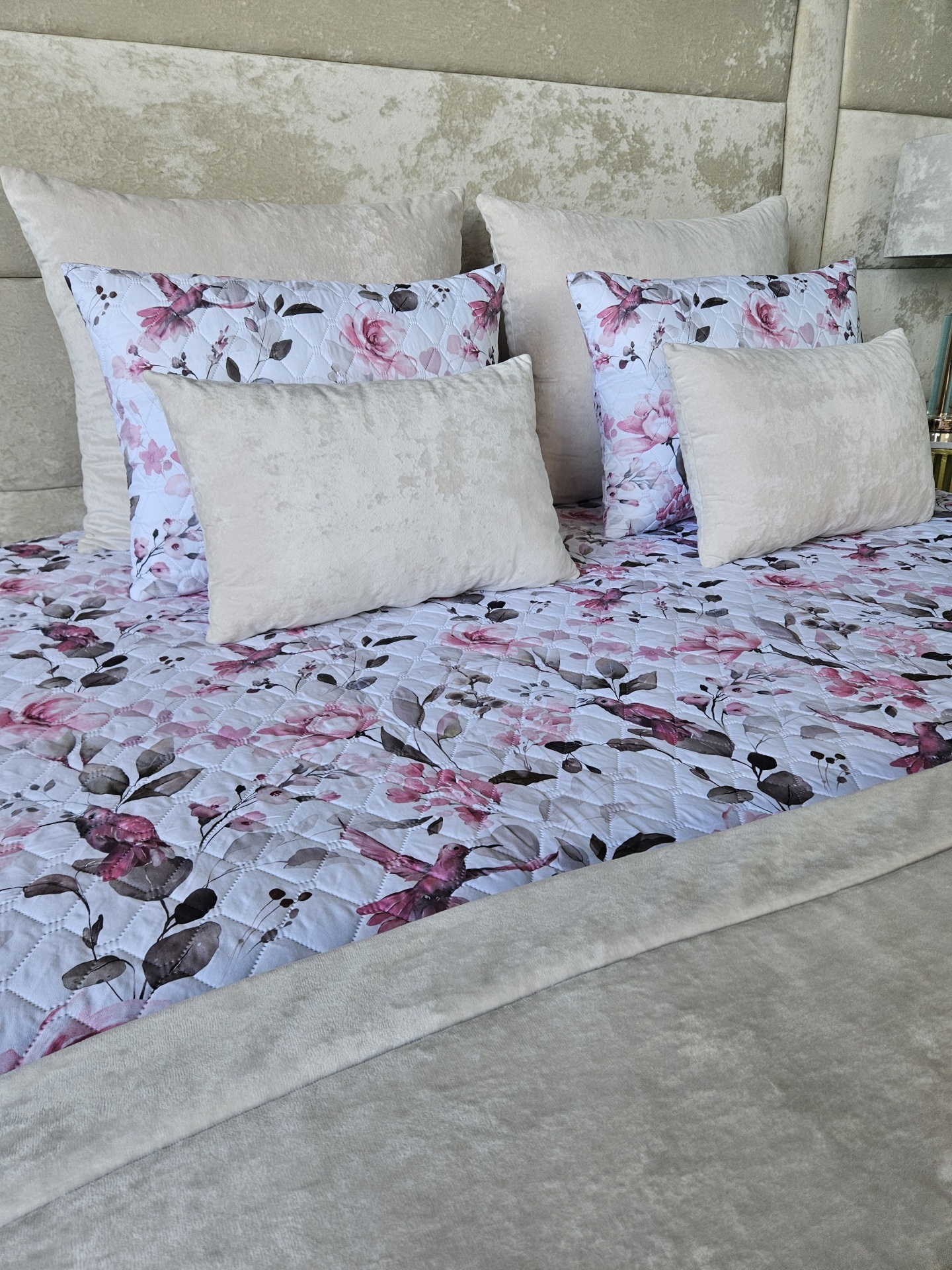 Roupa de cama com padrão floral rosa e almofadas beges
