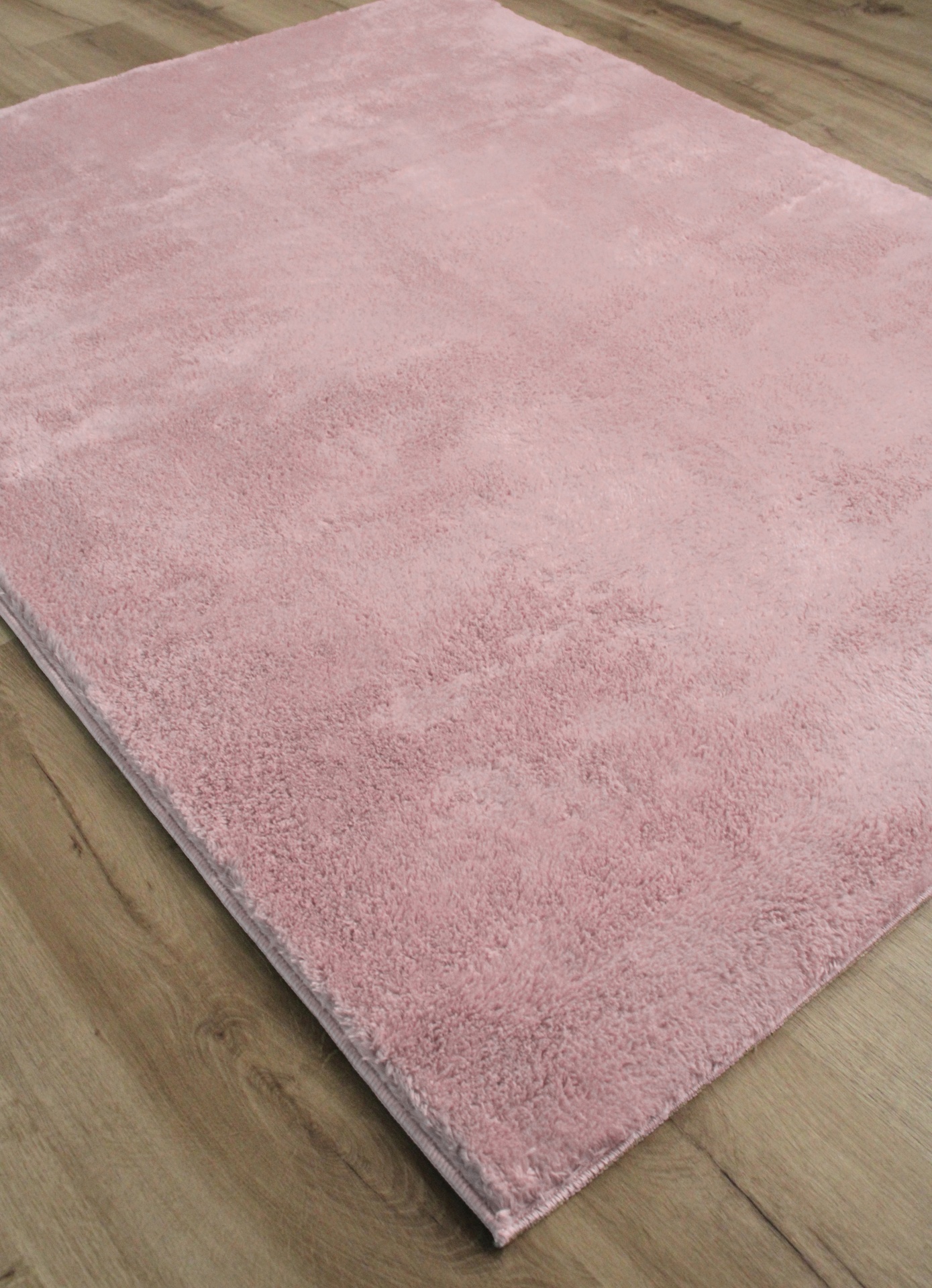 Tapete retangular de pelo alto rosa claro sobre chão de madeira