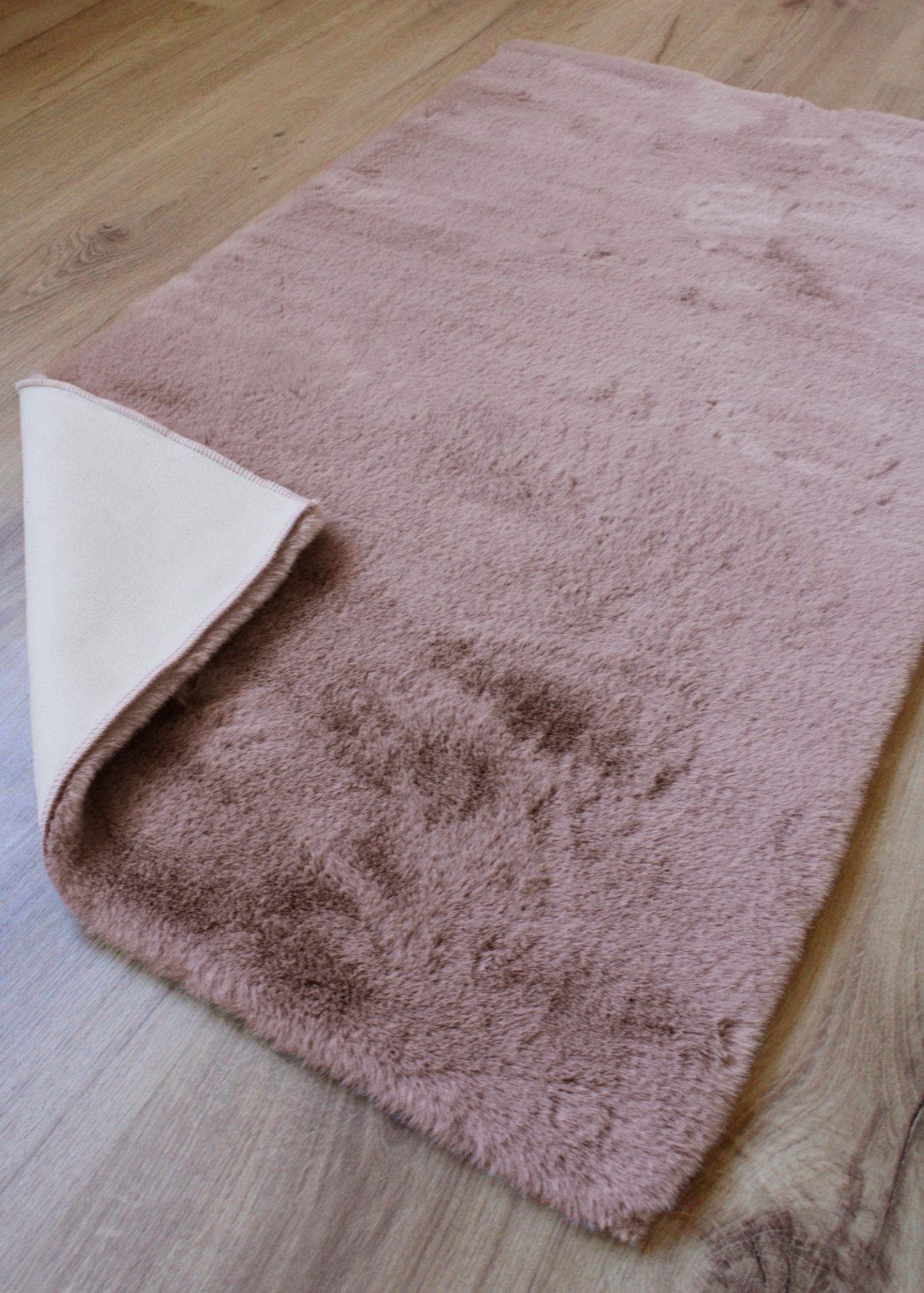 Tapete rosa claro com verso branco em chão de madeira clara