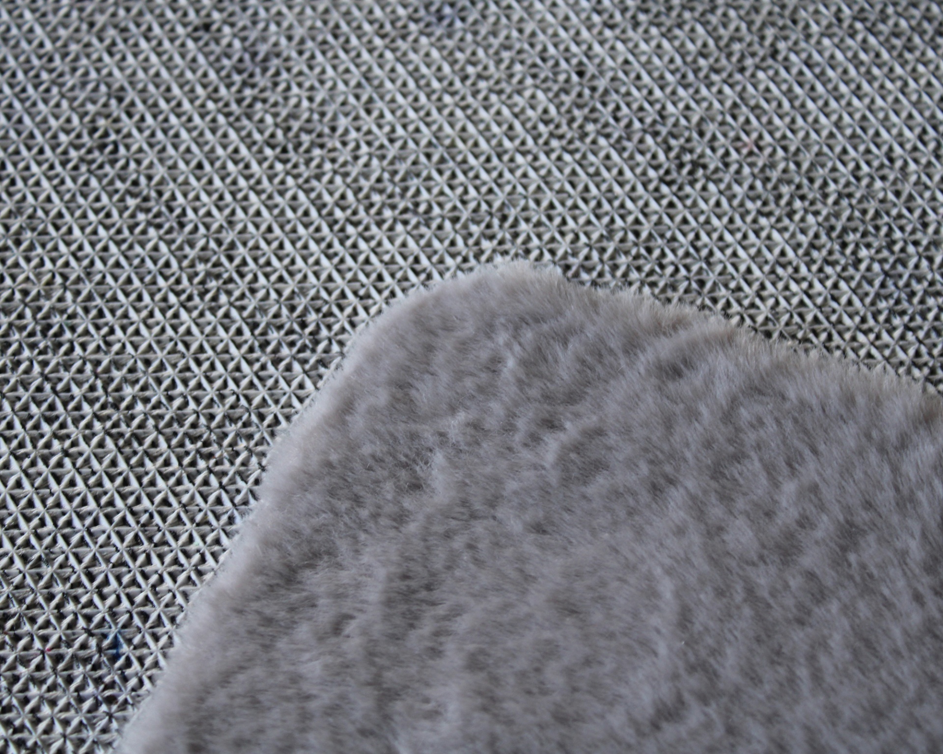 Tapete cinza claro felpudo sobre superfície cinza texturada