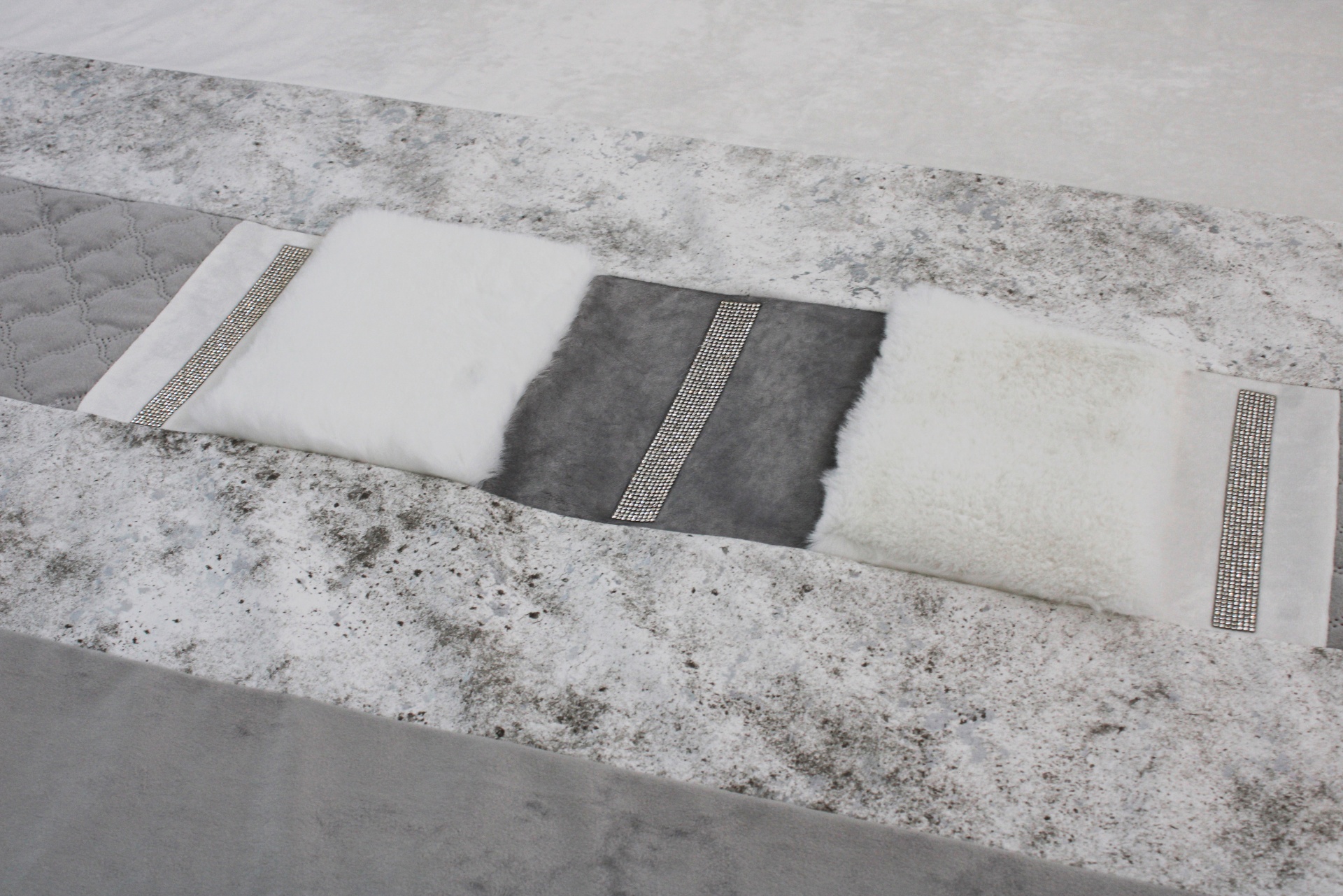 Faixa decorativa de tecido com diferentes texturas e cores cinza e branco sobre tapete cinza