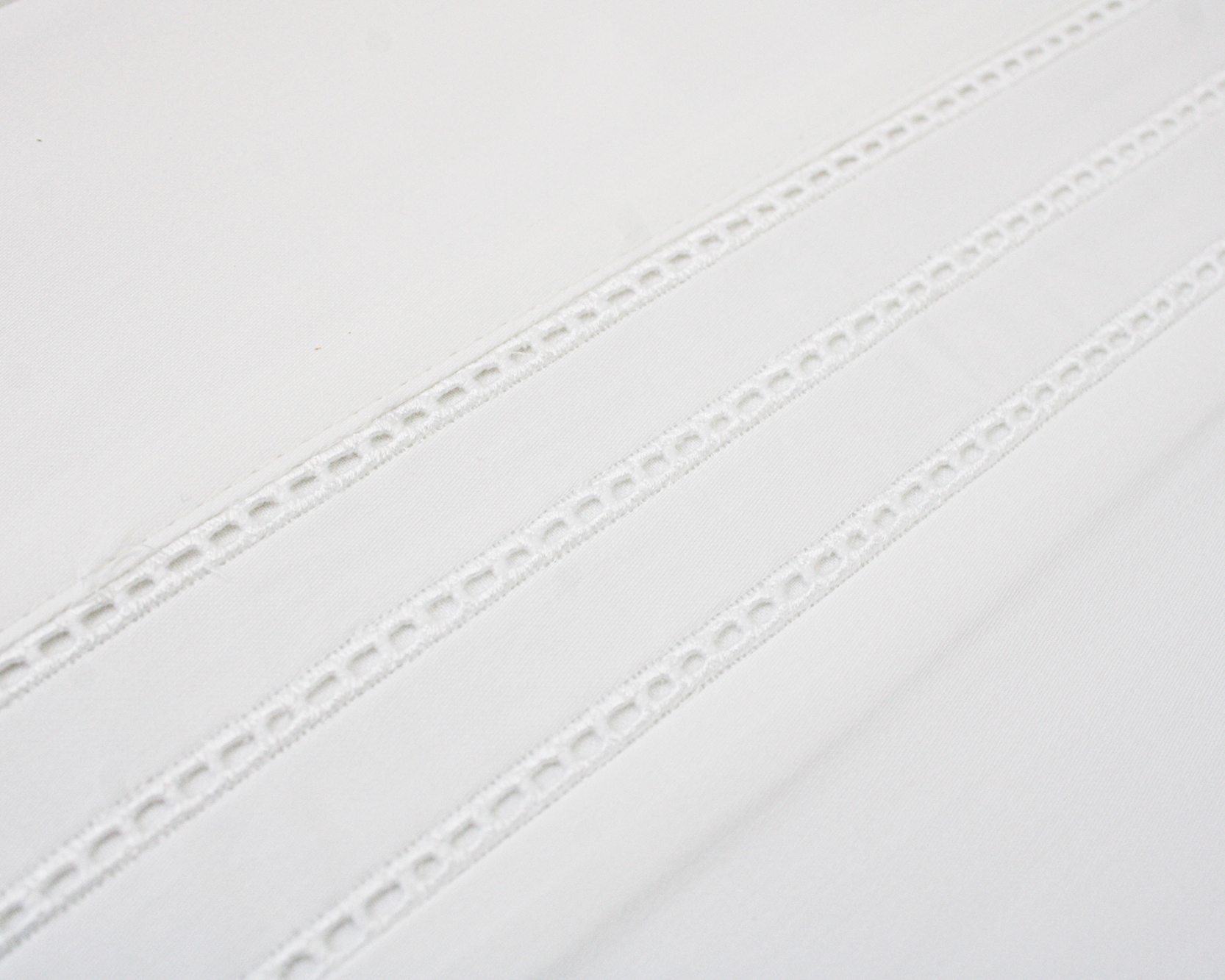 Tecido branco com faixas decorativas perfuradas