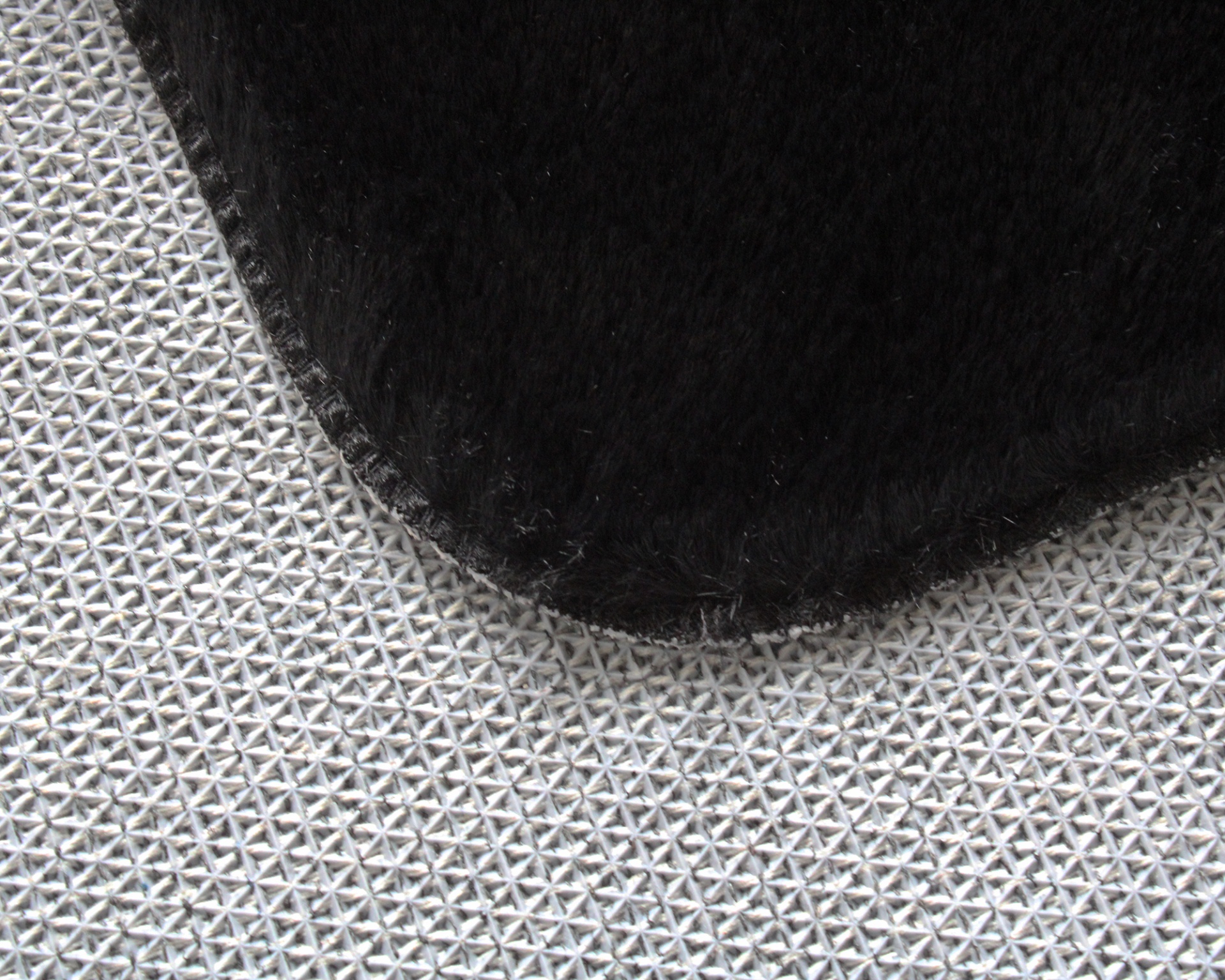 Tapete branco com padrão triangular e tecido preto sobreposto.