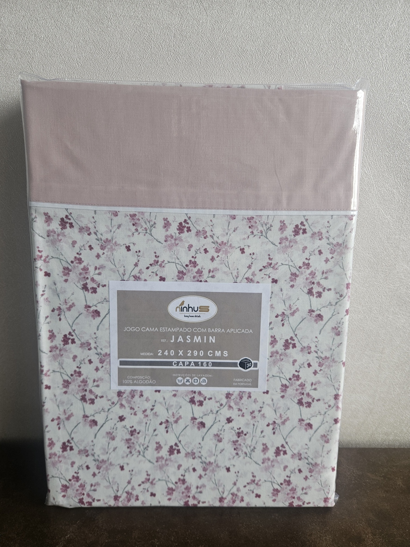 Jogo de cama rosa claro com padrão floral rosa escuro, embalado em plástico