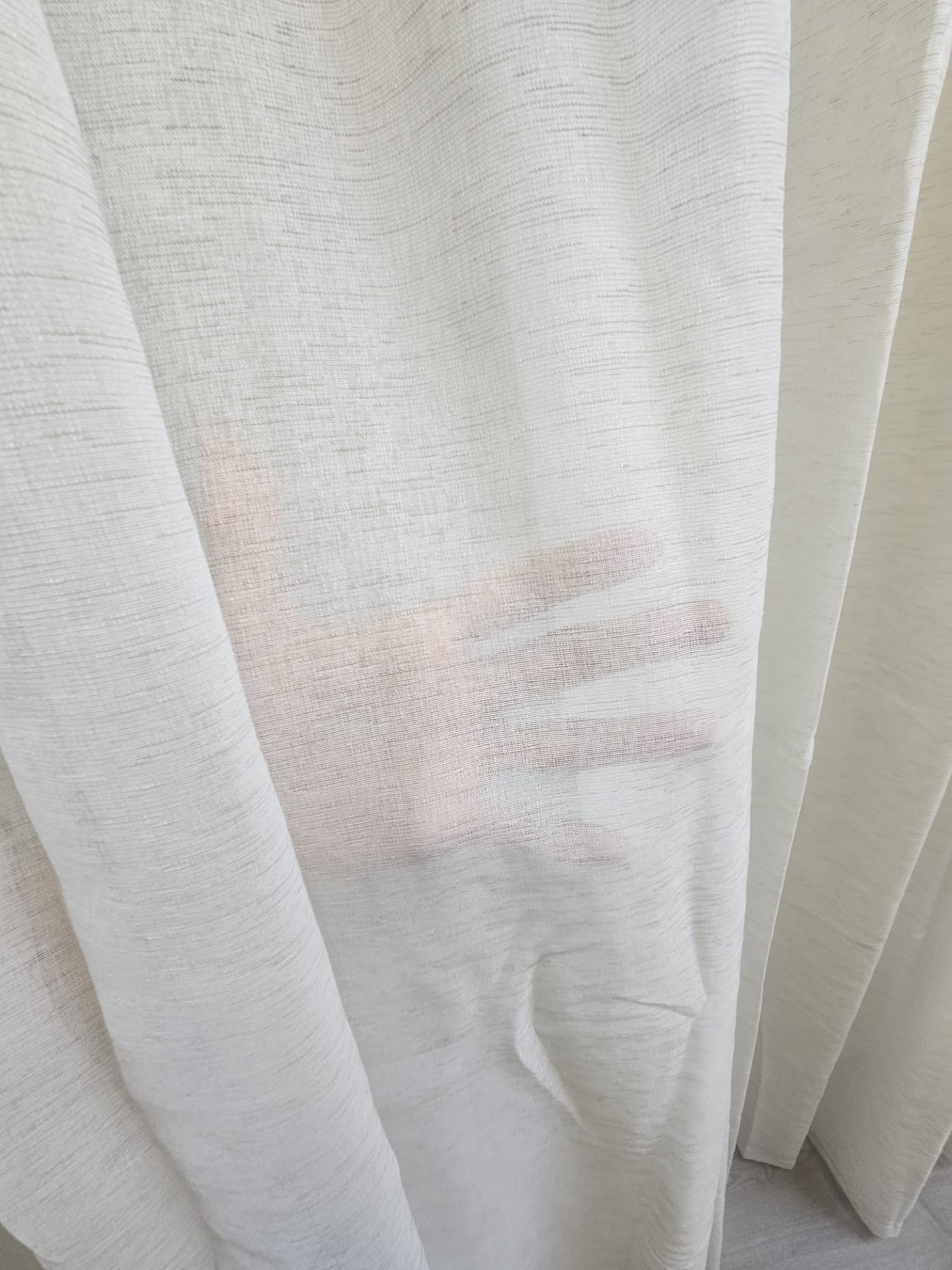 Cortina branca transparente com uma mão visível atrás