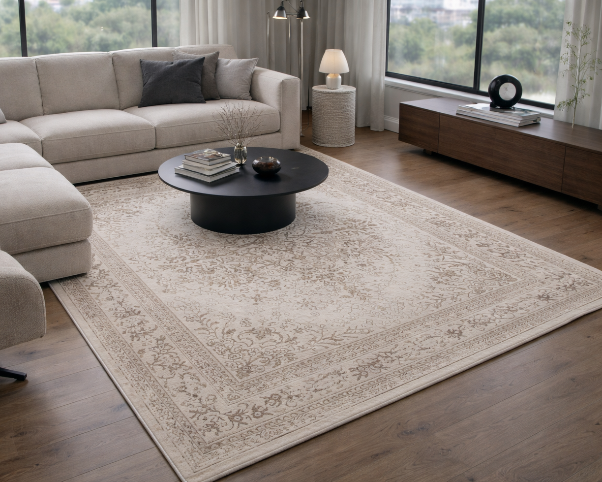 Sala de estar com sofá bege, mesa de centro preta e tapete decorativo bege com padrão floral.