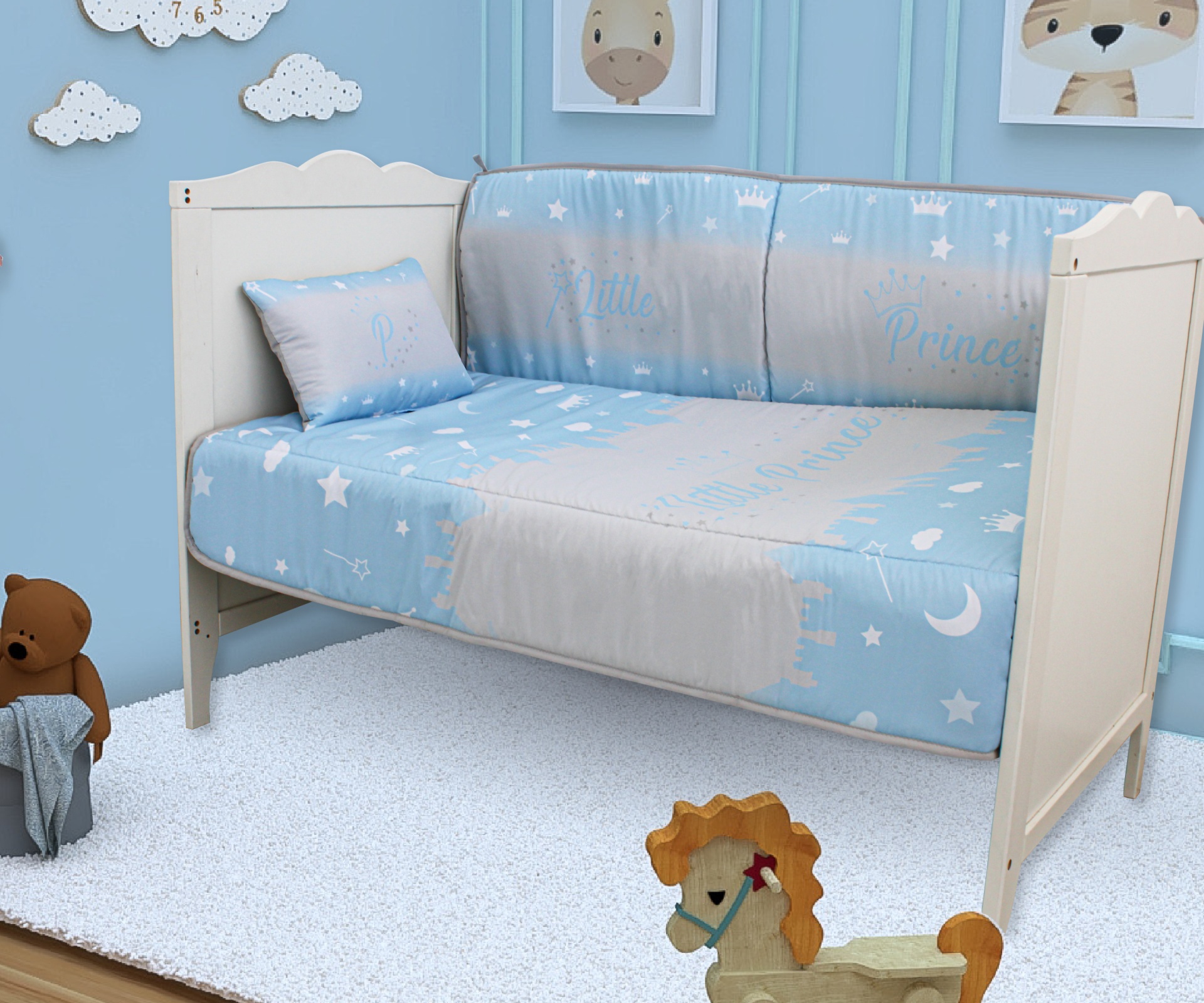 Cama infantil branca com roupa de cama azul clara estampada com estrelas e texto Little Prince