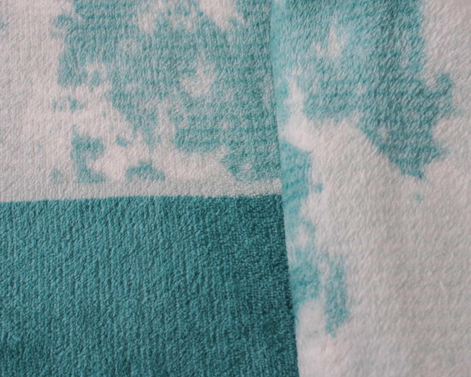 Toalha azul e branca com padrão pixelizado e textura felpuda.