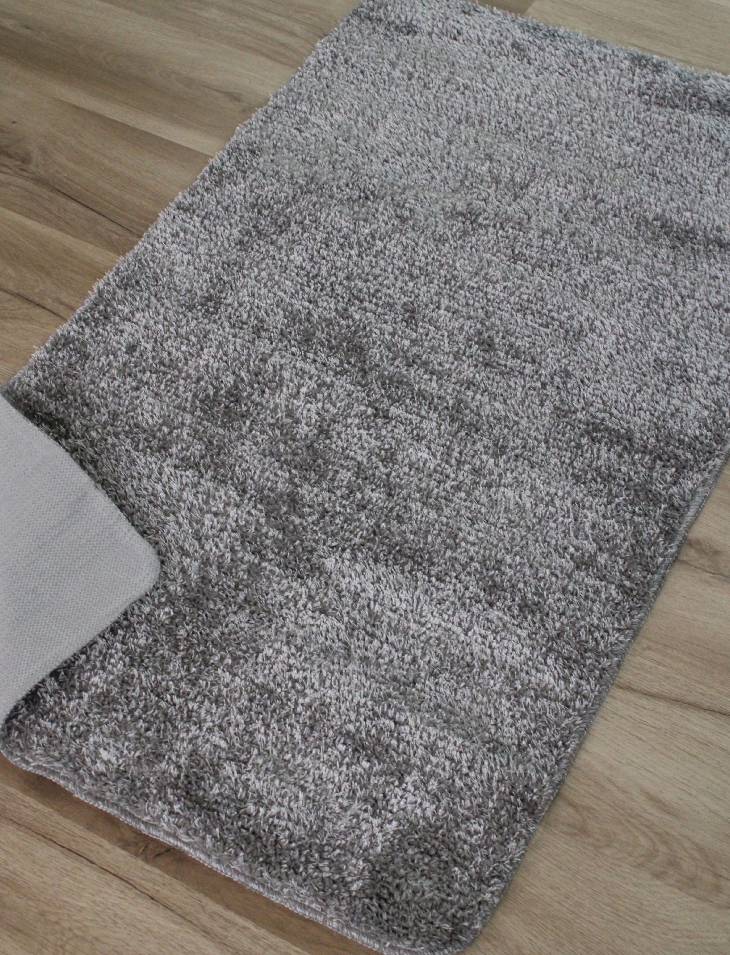 Tapete felpudo cinzento sobre chão de madeira