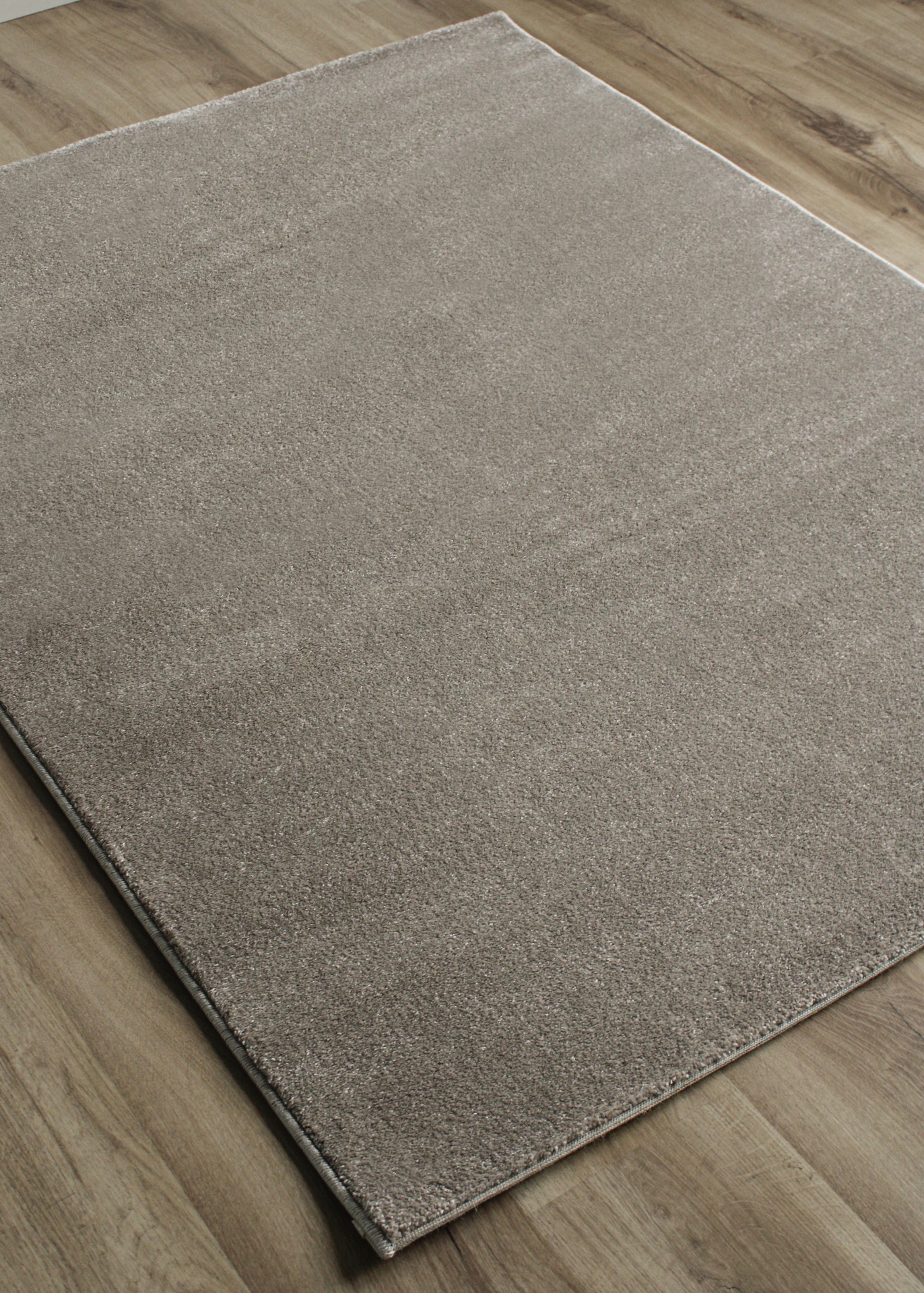 Tapete cinza claro sobre chão de madeira clara