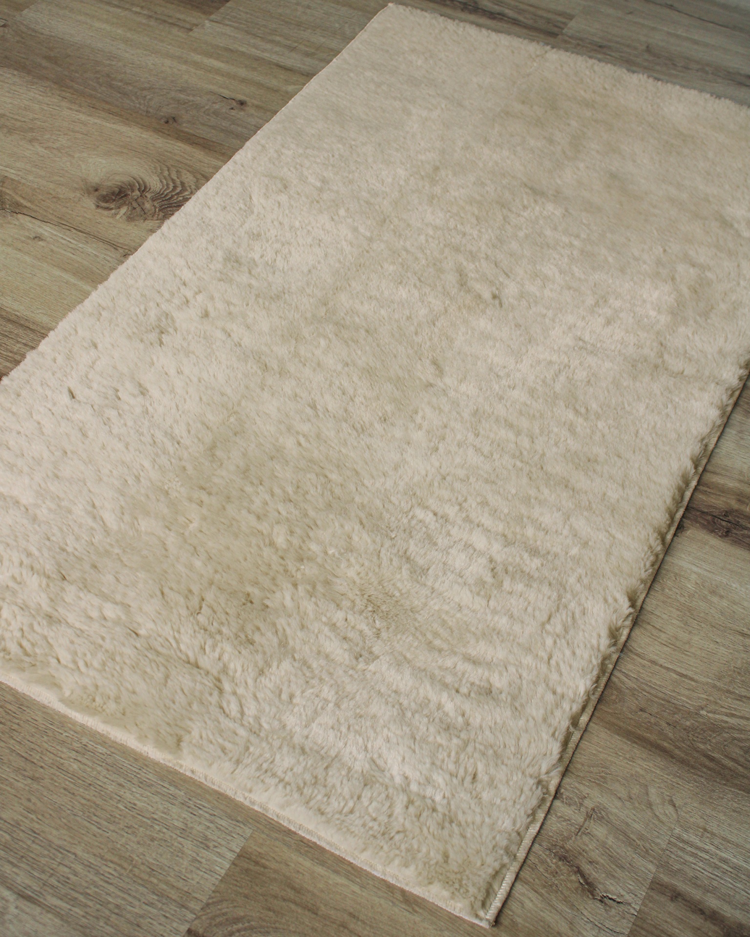 Tapete creme felpudo sobre chão de madeira clara