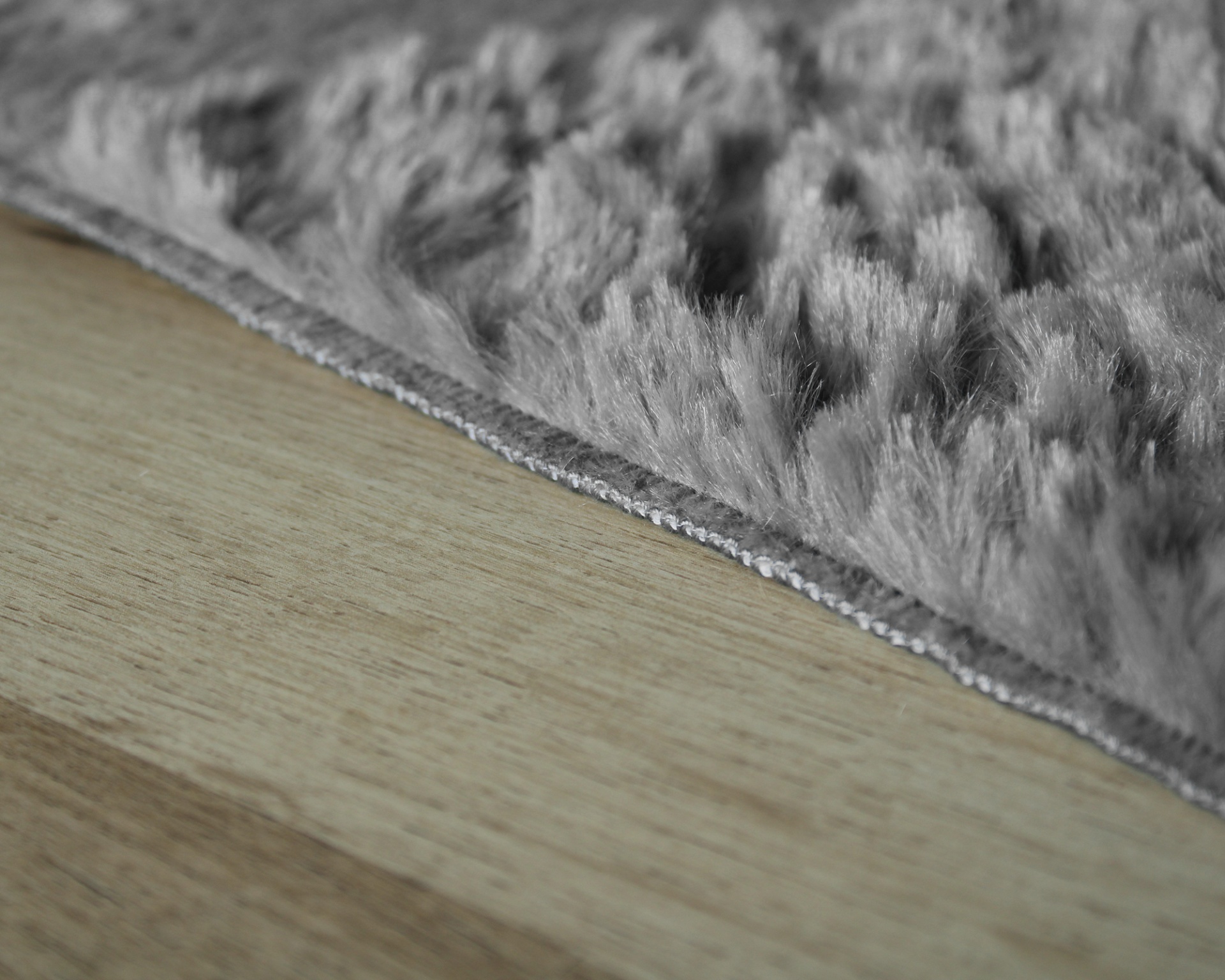 Tapete cinza felpudo sobre piso de madeira clara