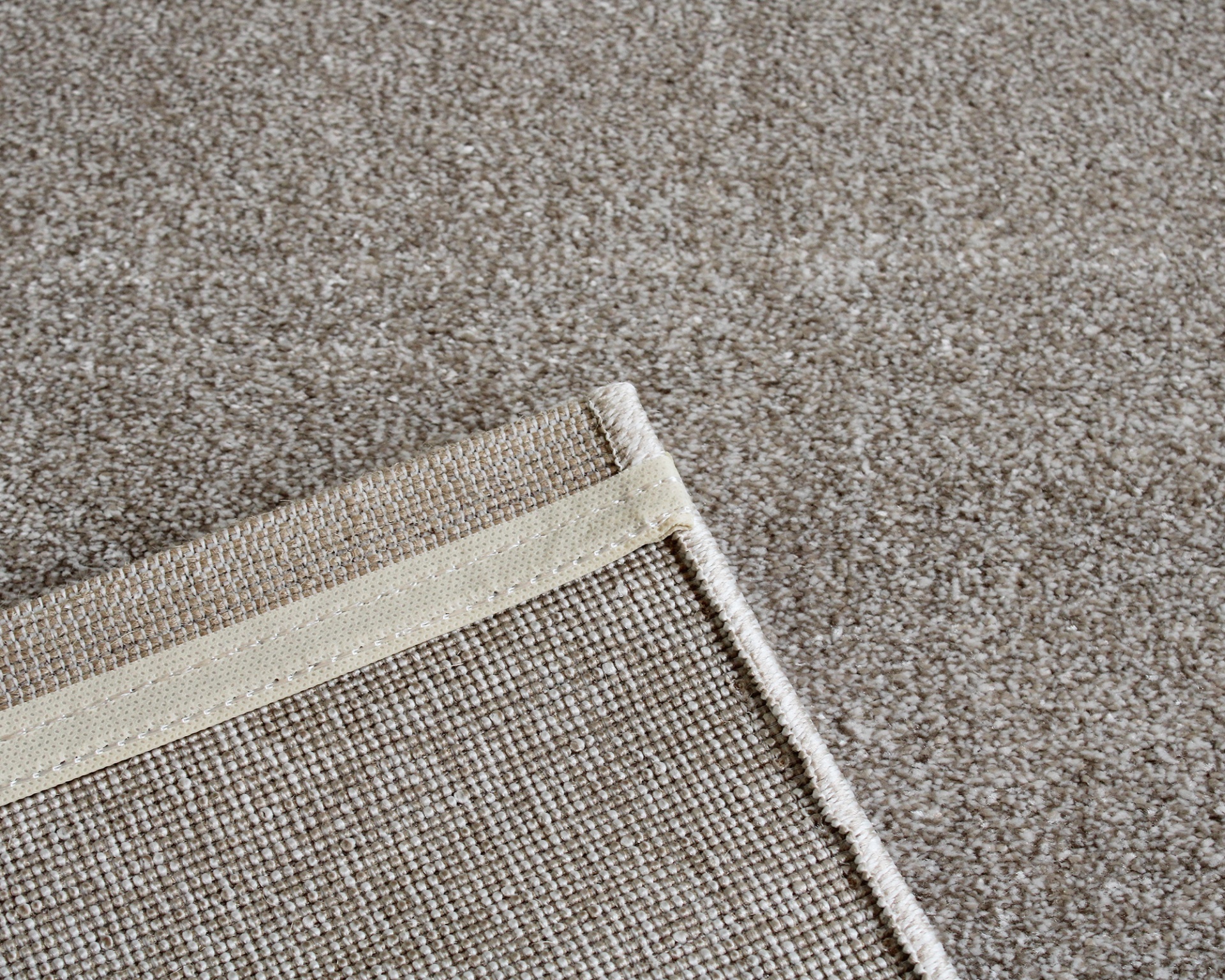 Tapete castanho claro com borda de tecido bege sobre superfície castanha escura