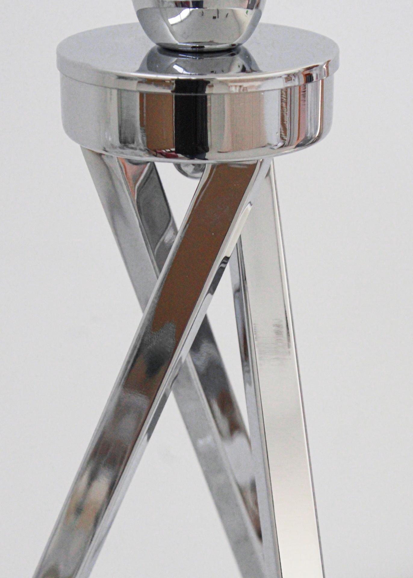 Base metálica prateada com pernas cruzadas e estrutura cilíndrica