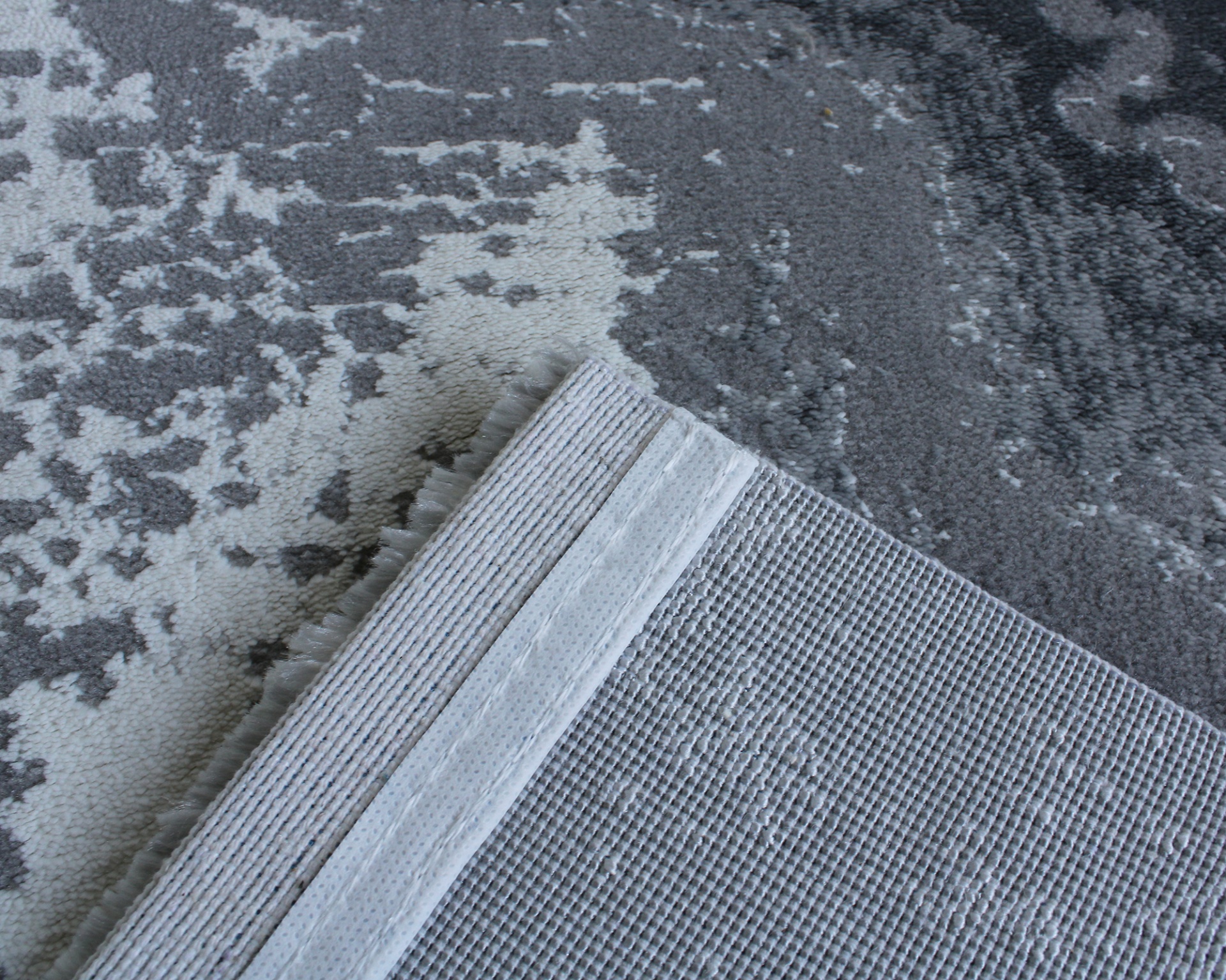 Tapete cinzento e branco com padrão abstrato e verso antiderrapante