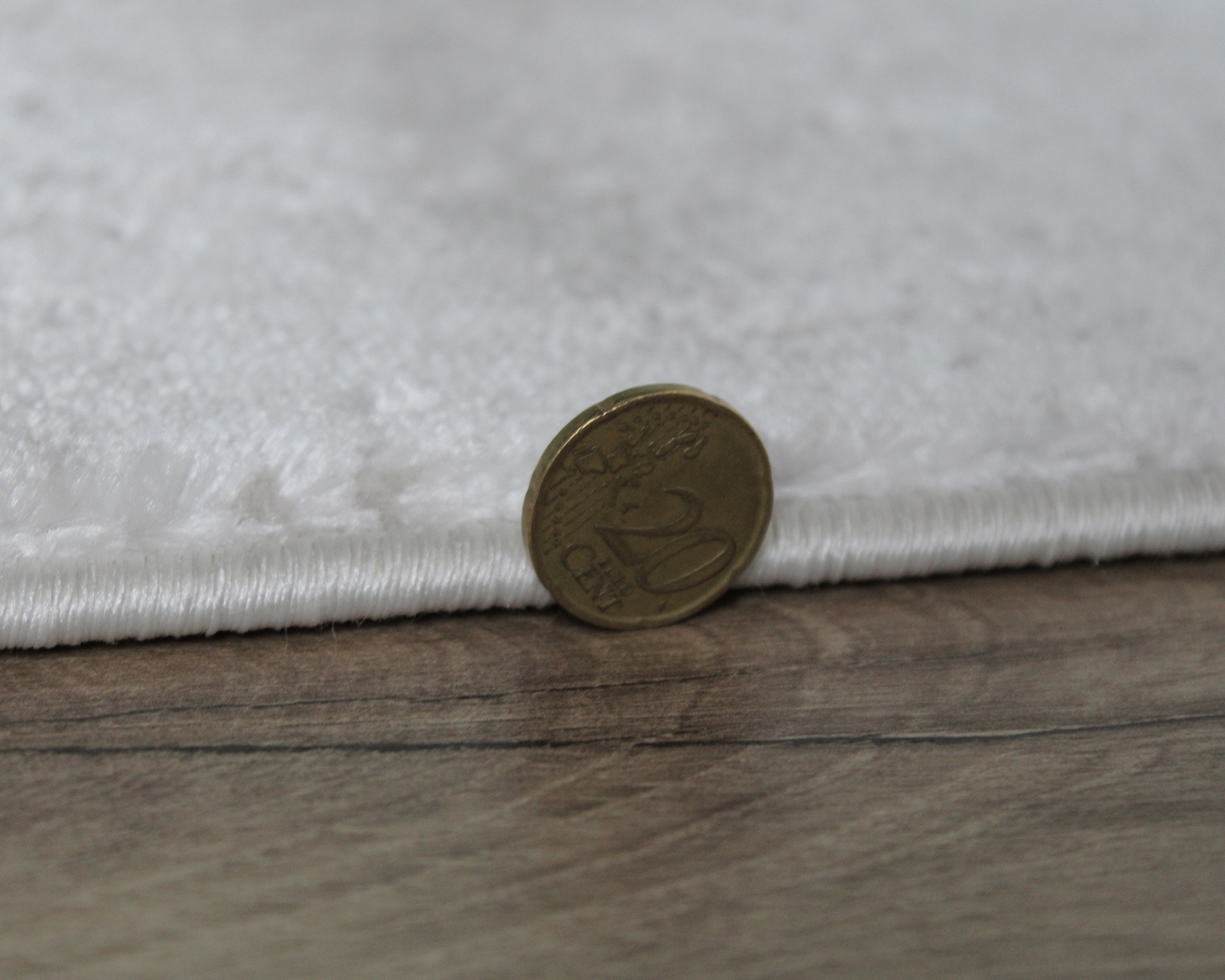 Tapete ou carpete branco com moeda de 20 Cêntimos de Euro para medir espessura