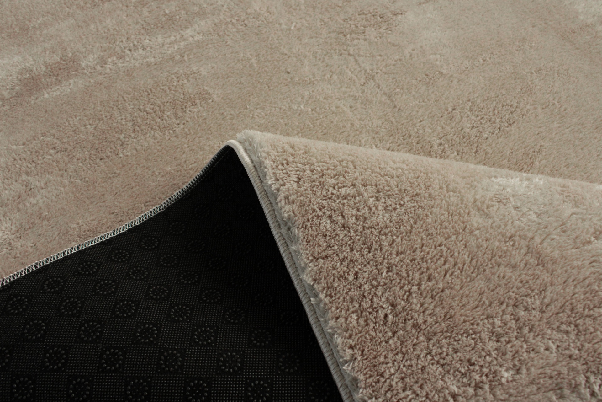 Tapete bege com parte inferior preta antiderrapante em chão bege