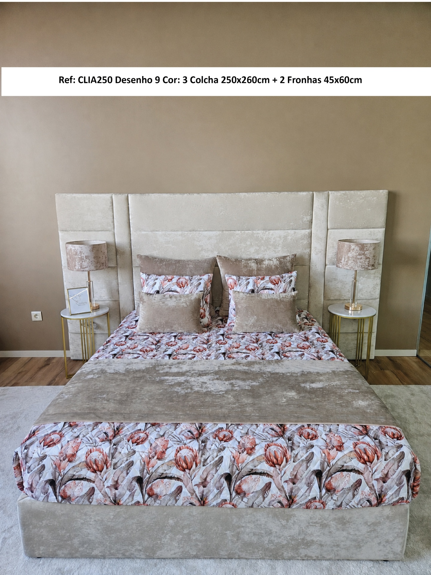 Cama com colcha floral cor de rosa e bege com cabeceira estofada e duas mesas laterais com abajures.