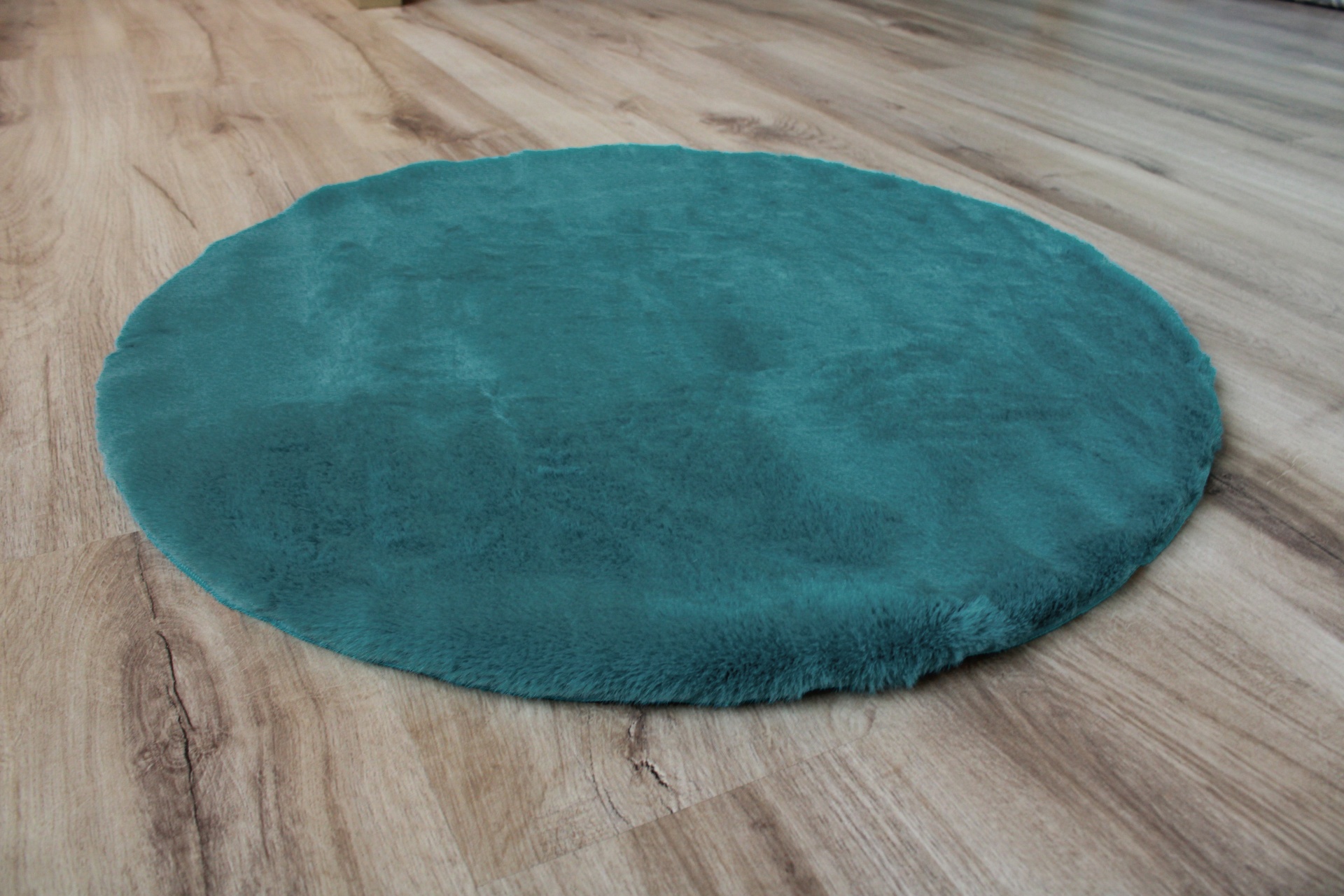 Tapete redondo verde-azulado sobre pavimento de madeira clara