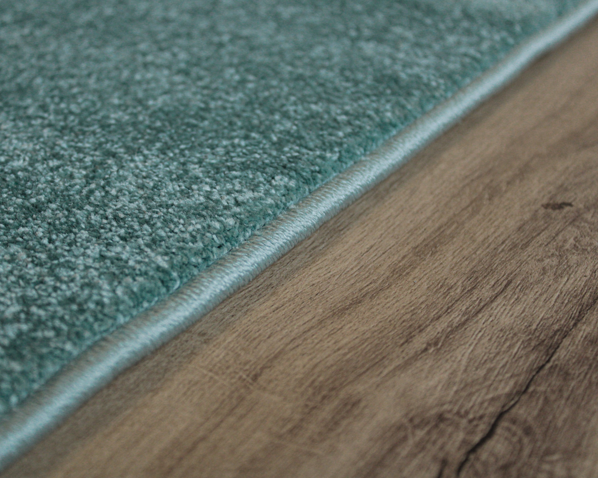 Tapete verde com textura macia em pavimento de madeira castanha