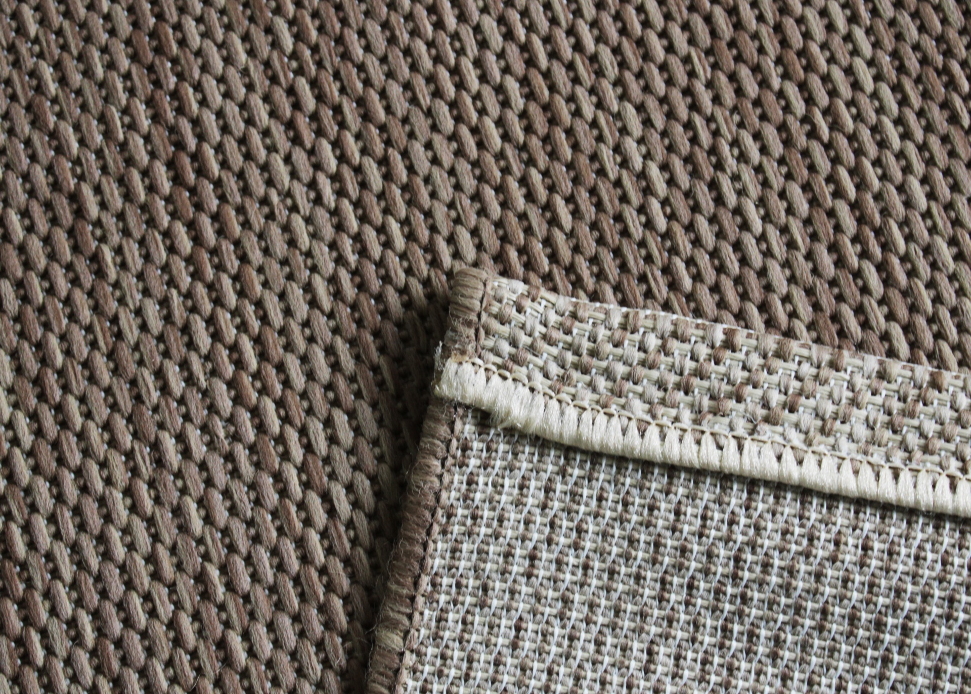 Tapete castanho com borda costeada bege claro sobre tapete castanho com textura diferente