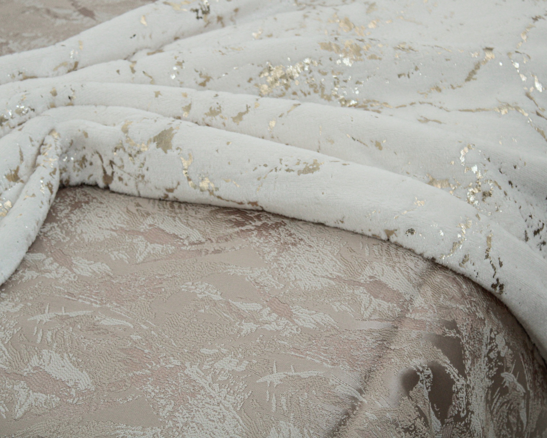 tecido branco com padrão dourado sobre tecido bege estampado