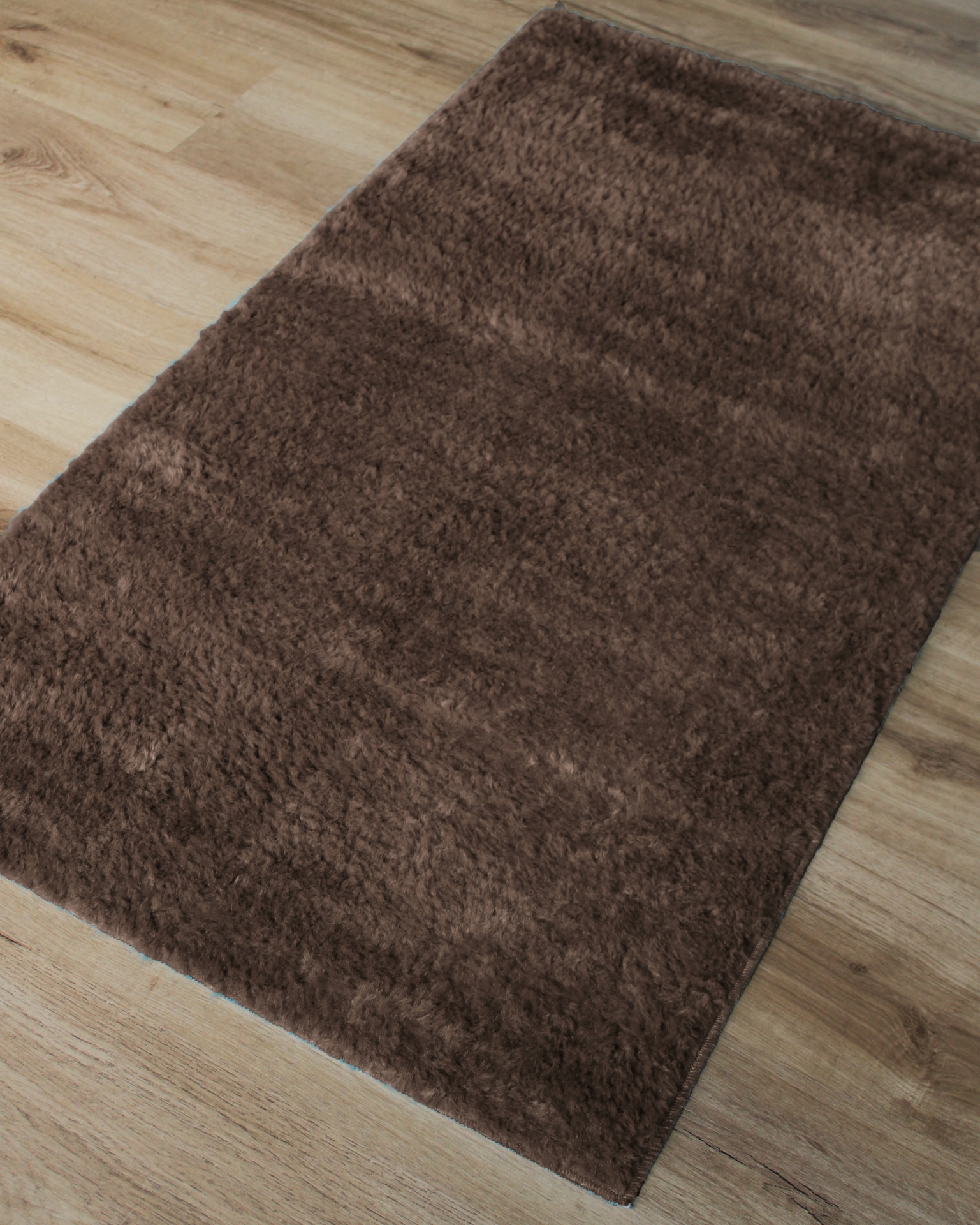 Tapete felpudo castanho escuro sobre chão de madeira