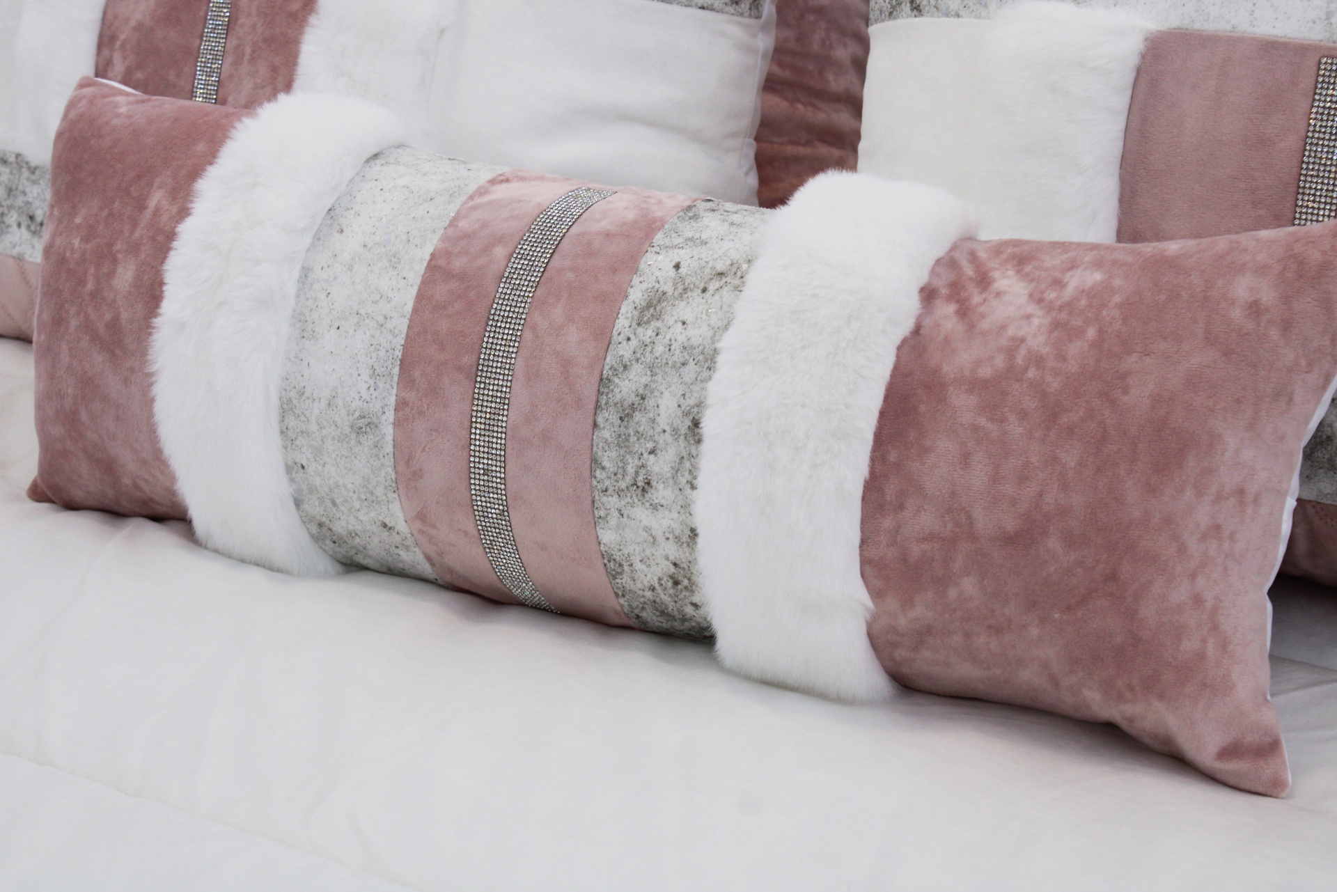 Almofada retangular decorativa com faixas em pelúcia branca, veludo rosa e tecido prateado